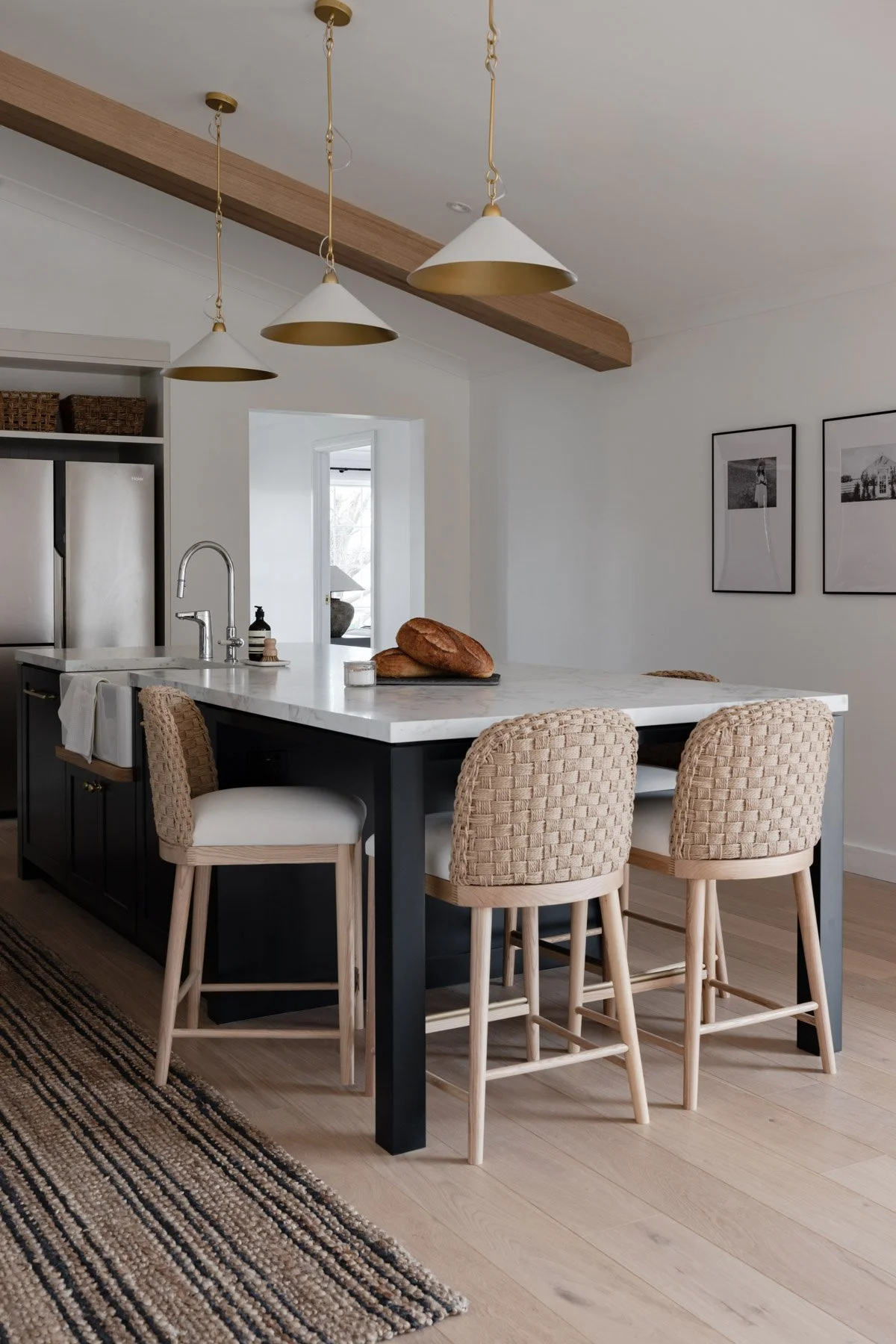 A stylish kitchen interior by Oak & Olive Homes with dark navy island and woven stools, highlighting a modern aesthetic & inviting atmosphere