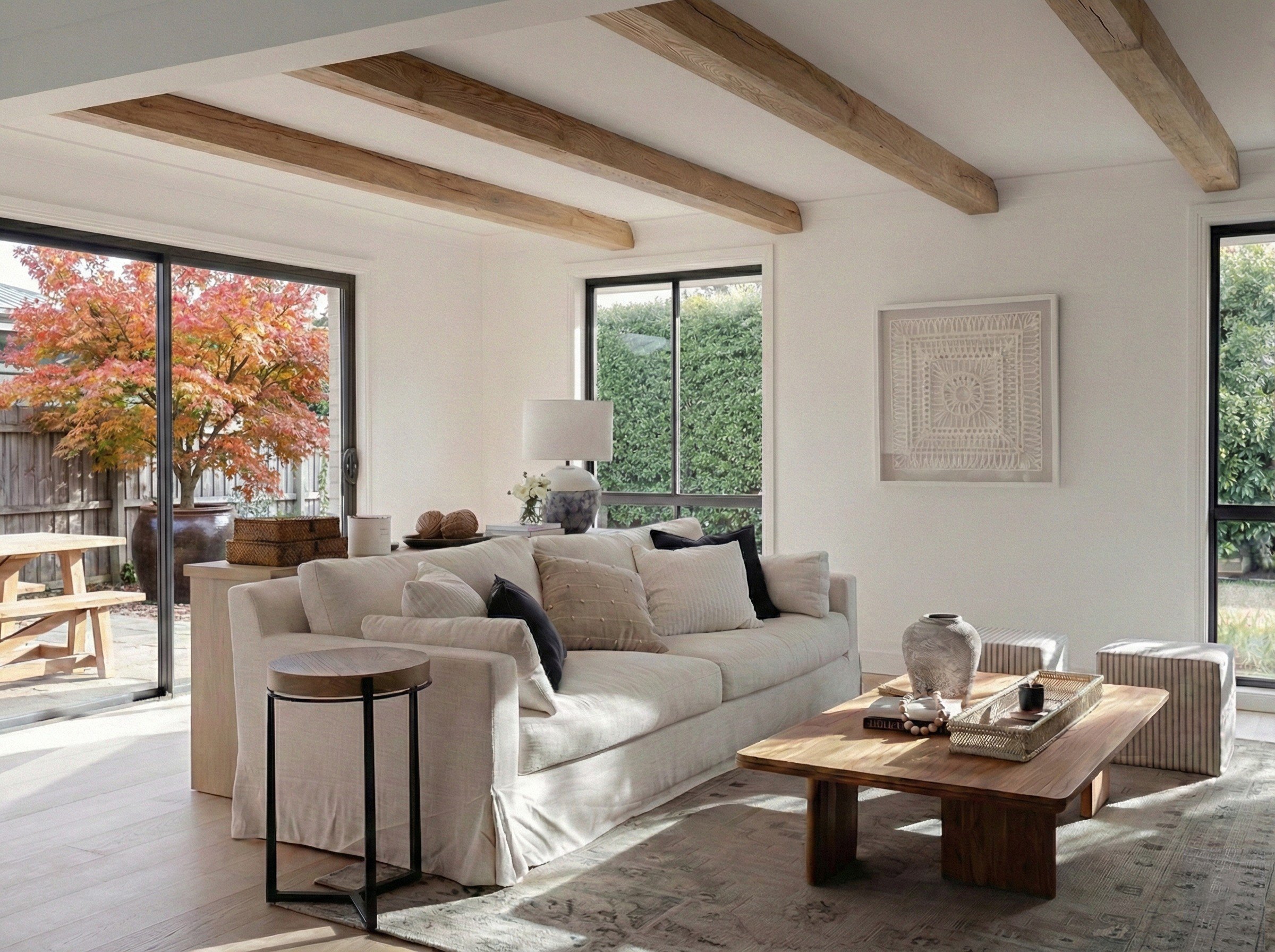 Bright, modern, cozy living room by Oak & Olive Homes featuring a large, off-white slipcovered sofa, wooden coffee table, light oak wood floors, and large windows overlooking winter trees