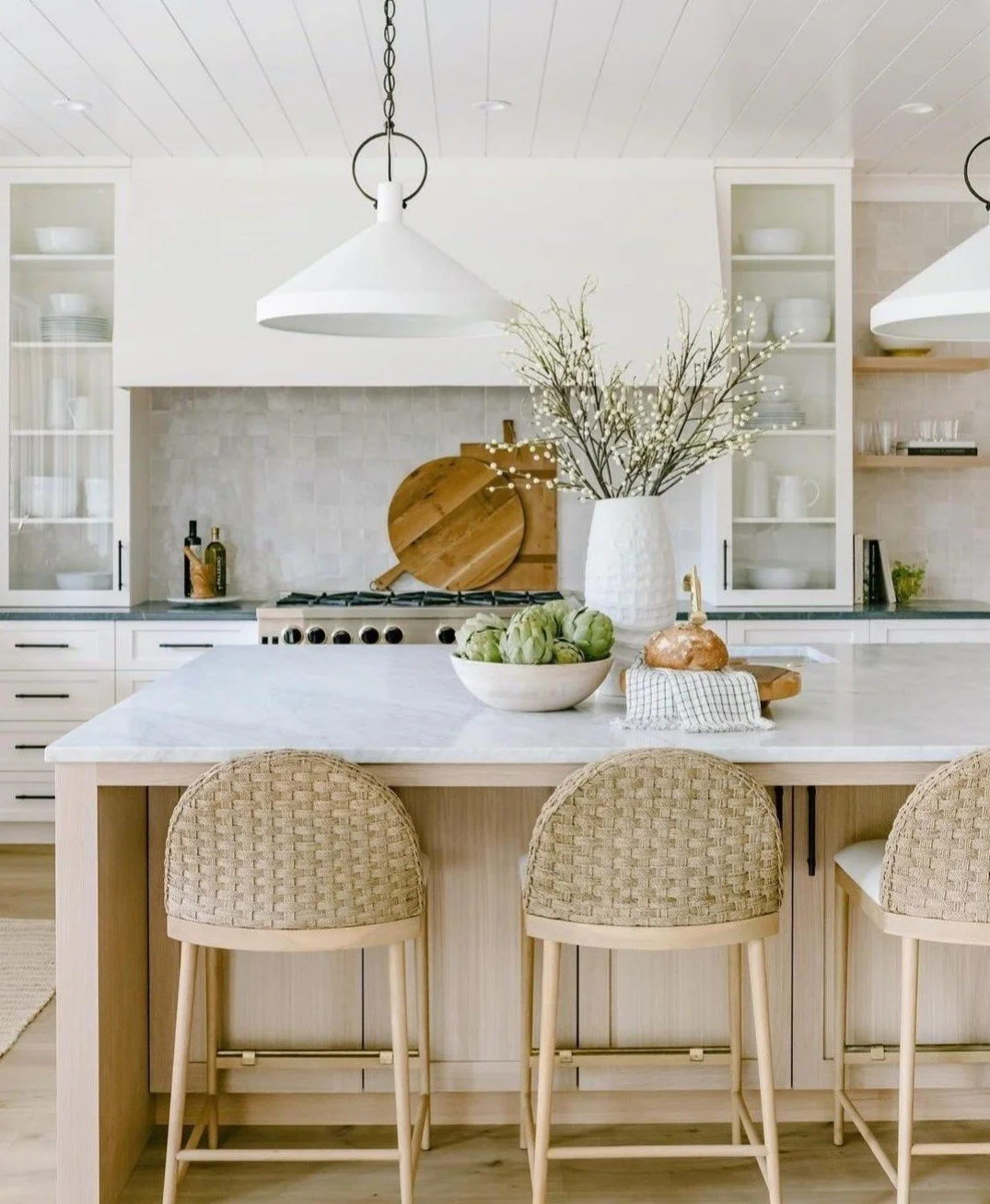 Beautiful bright kitchen with v-groove ceiling lining, large island with marble benchtops, white pendants and woven counter stools