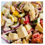 A bowl of chicken salad with chopped chicken, red onions, celery, and tomatoes