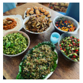 A variety of dishes including salads, rice, beans, and sides on a wooden table.