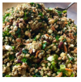 A close-up of a bowl of cooked couscous salad with vegetables and herbs.