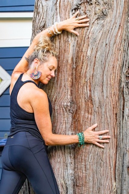 Woman hugging a large tree trunk outdoors