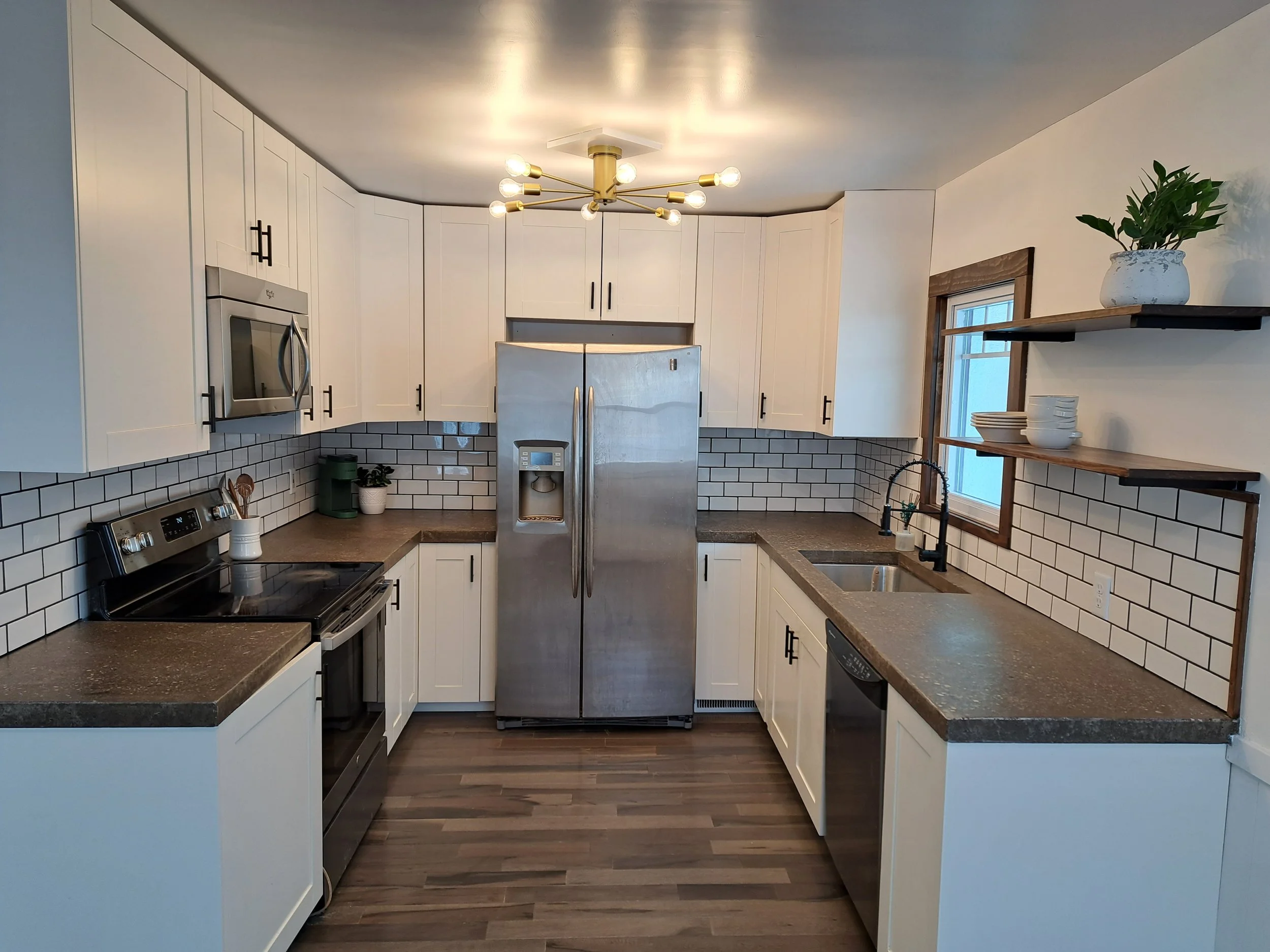 St Paul kitchen remodel with concrete countertops, white shaker cabinetry with black hardware and hardwood shelves and flooring