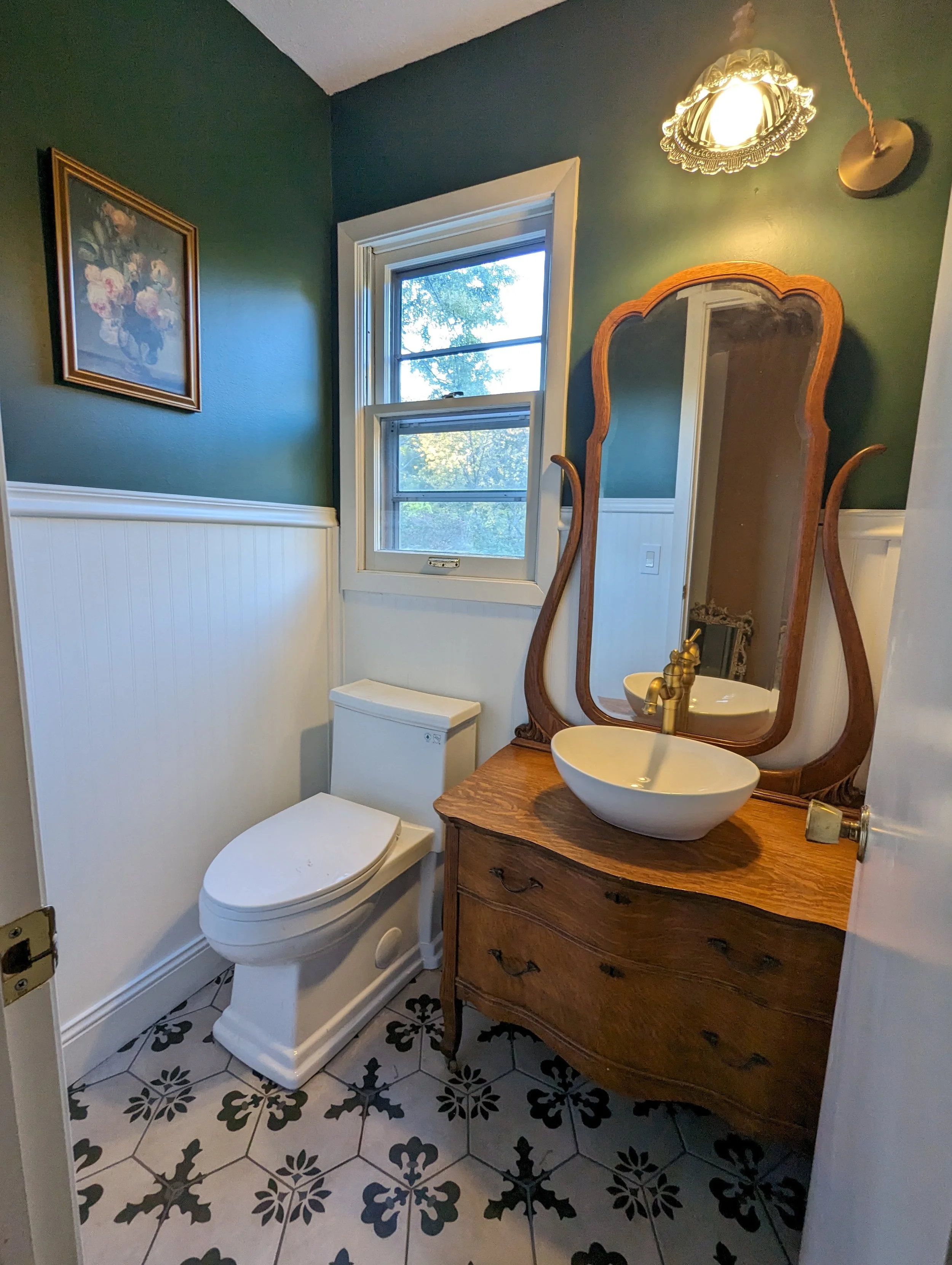 Powder half bathroom with beadboard paneling, vintage dresser mirror vanity, vessel sink and swag light