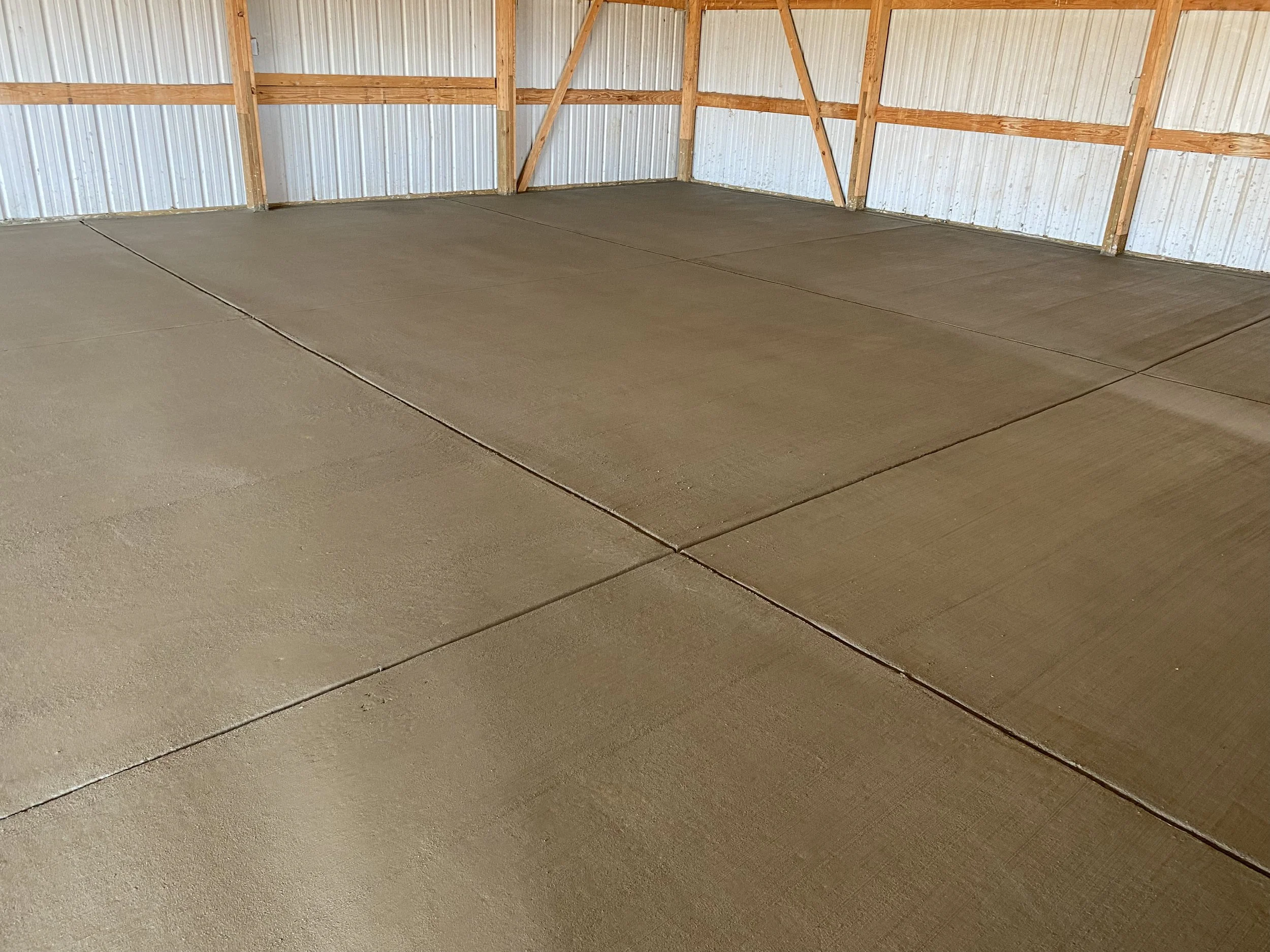 Empty indoor space with newly poured concrete floor and wooden framing on the walls.