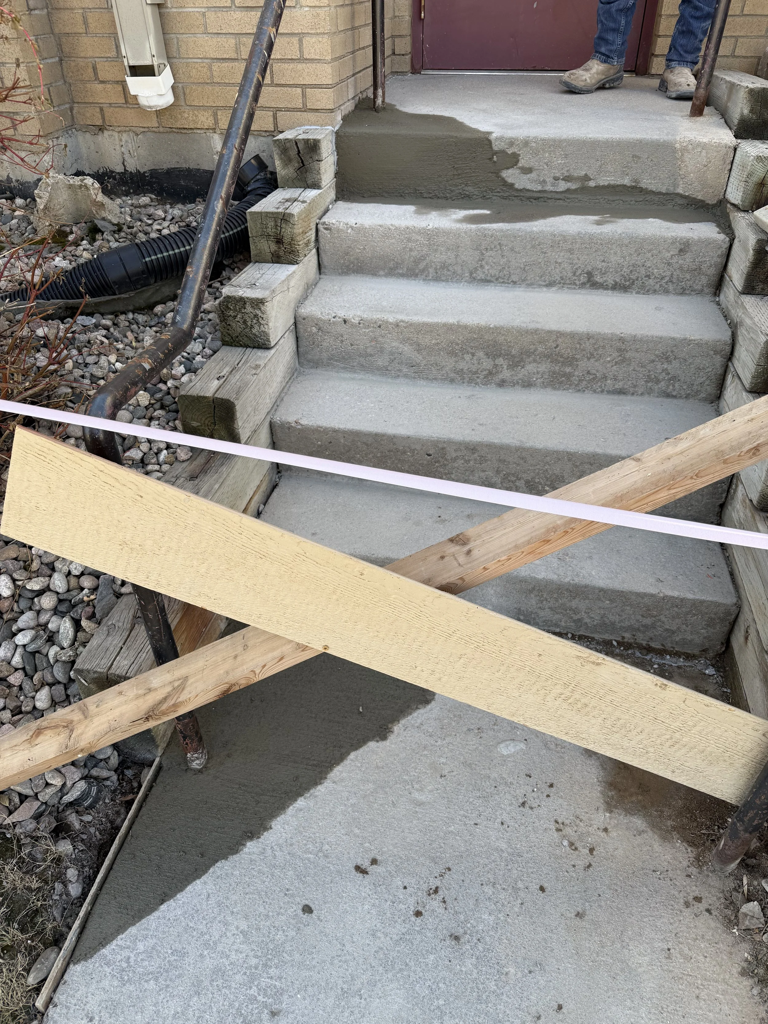 Construction site with concrete stairs being poured, wooden supports, and construction tools and materials around.