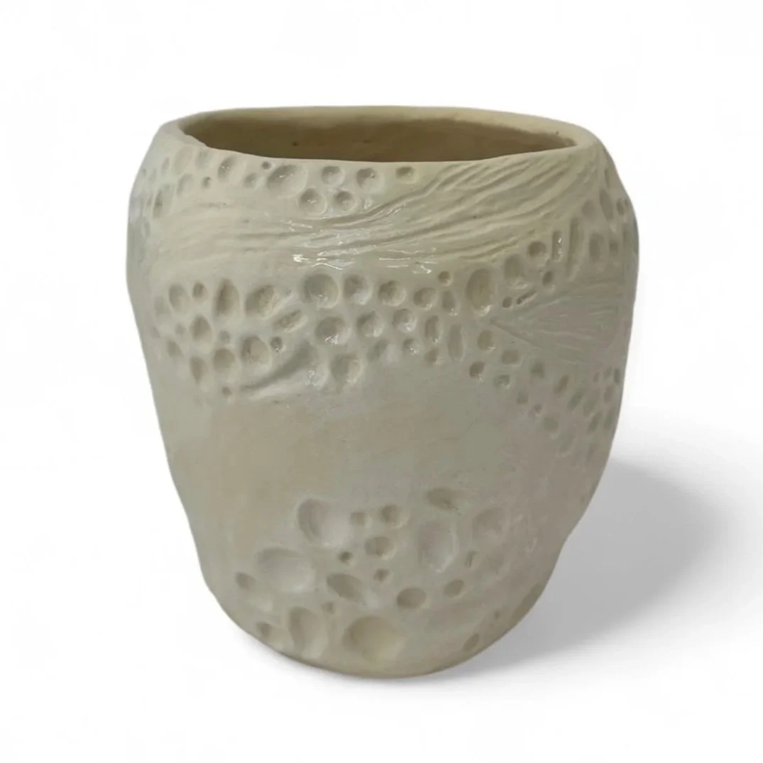 Cream-colored ceramic vase with textured, crater-like surface patterns.