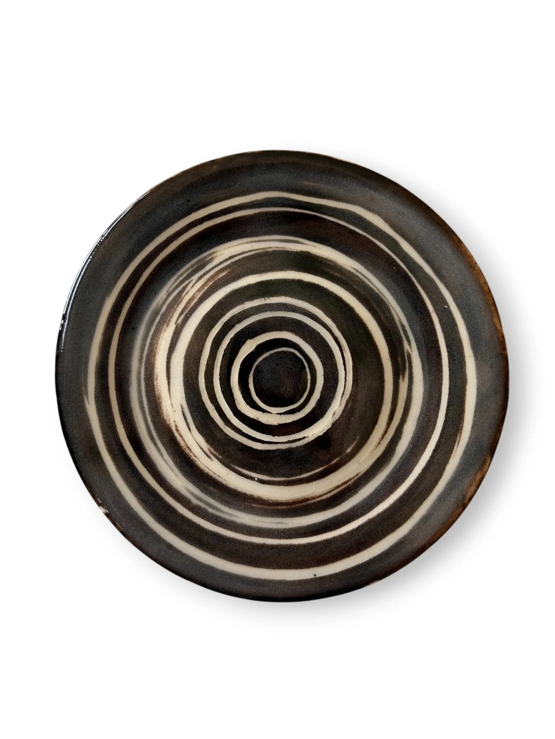 A black ceramic plate with a white non-concentric circle pattern.