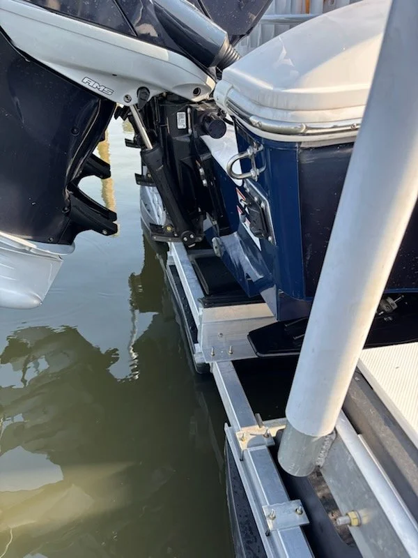 Close-up of a boat's outboard motor connected to a dock with water underneath.