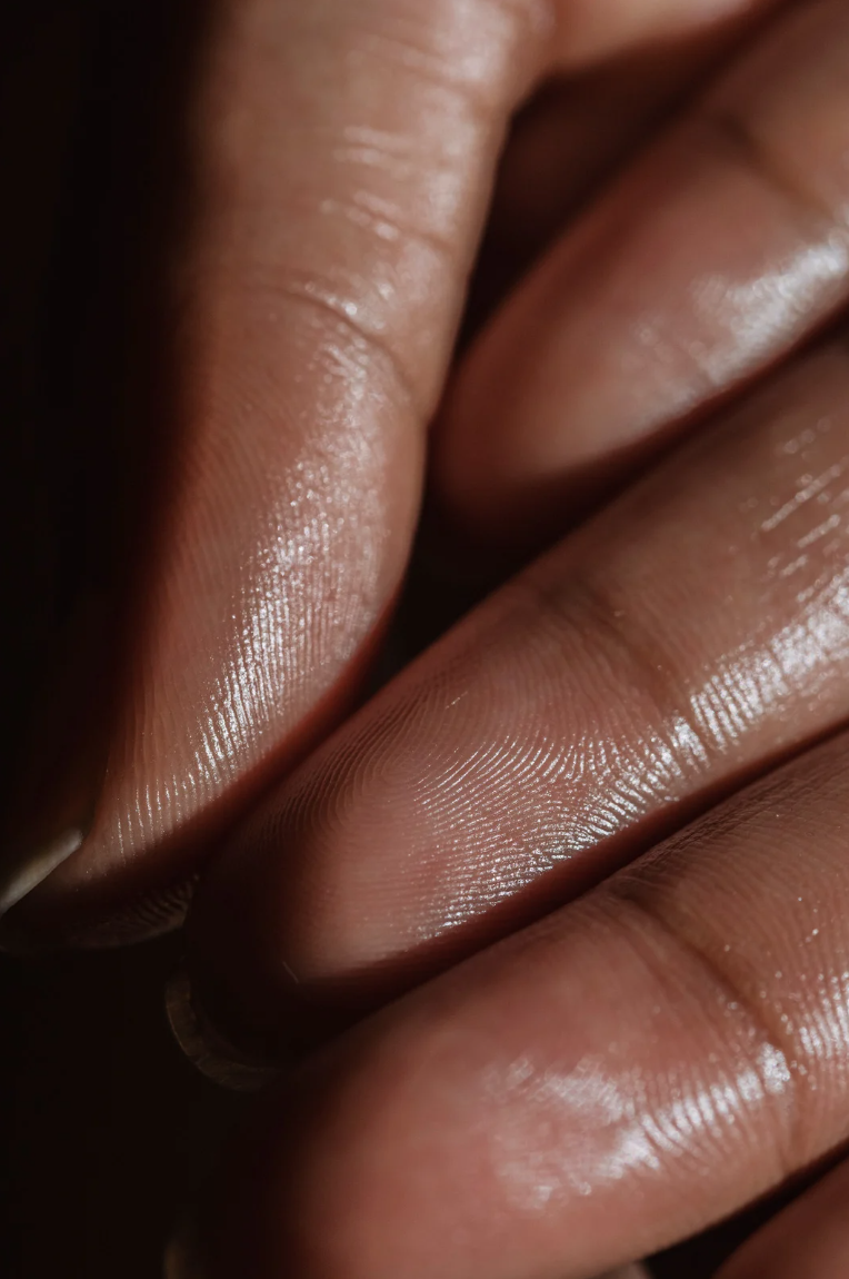Close-up of fingers with detailed skin texture and natural shine.