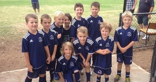 Group of young boys and girls in soccer uniforms on a soccer field.