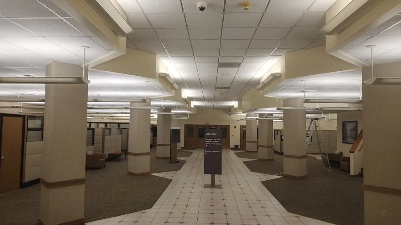Empty office reception or waiting area with tiled walkway, cubicles or booths, and a sign in the center.