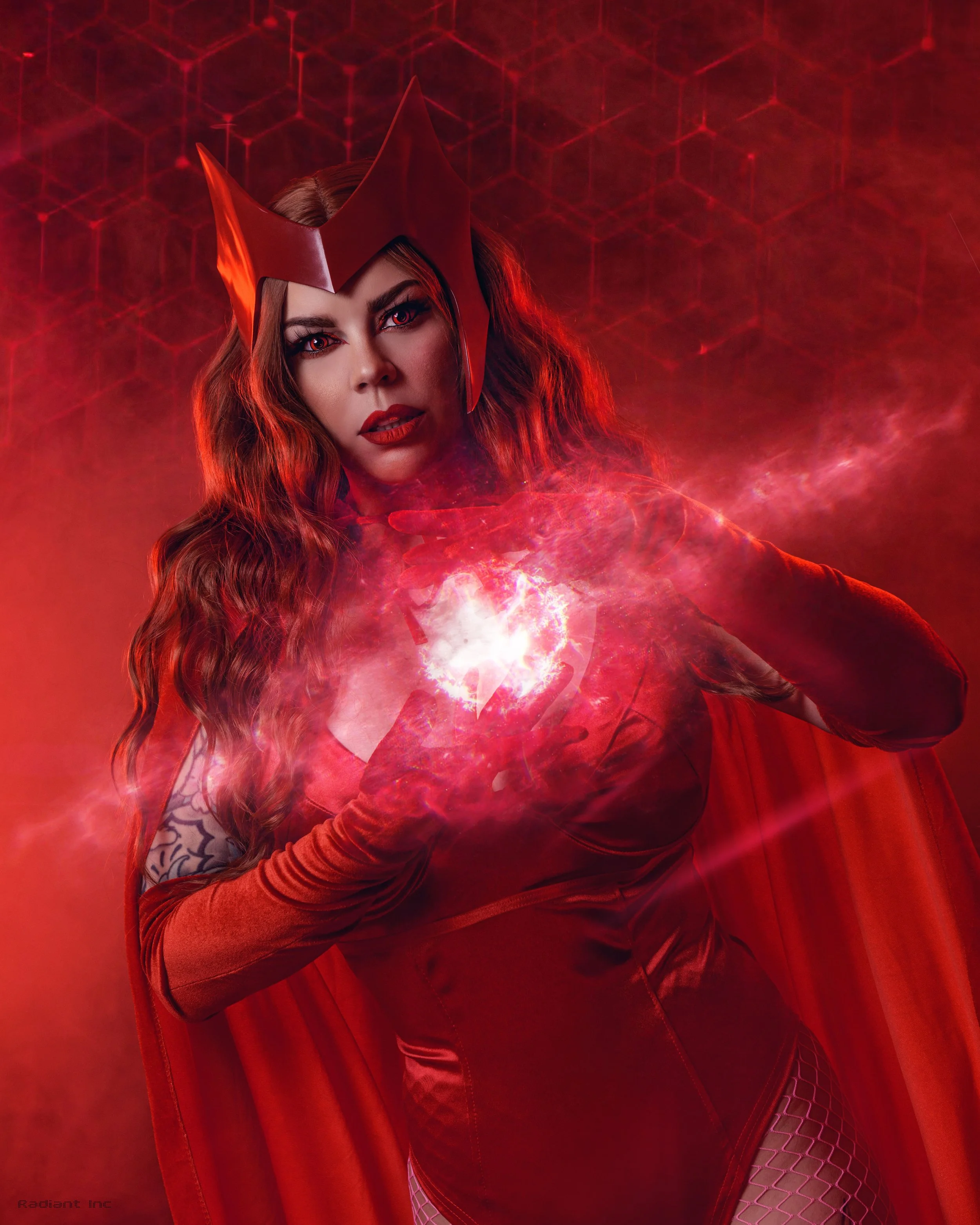 A woman dressed as a comic book villain or sorceress with a red costume and power emitting from her hands.
