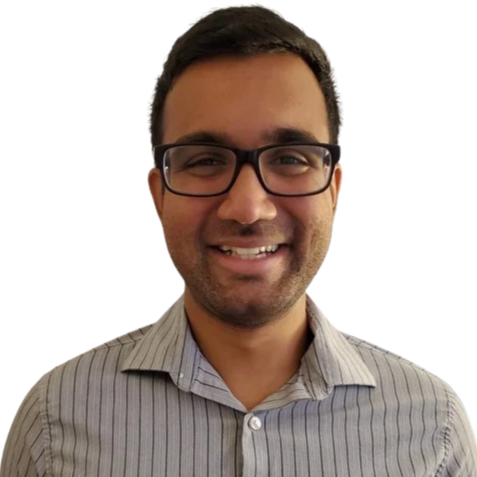A smiling man with glasses and dark hair wearing a gray striped button-up shirt.