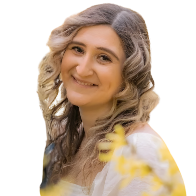 A young woman with wavy, blonde hair smiling outdoors with yellow flowers in foreground.