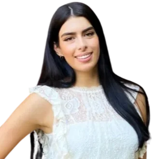 Young woman with long black hair smiling, wearing a white lace top and black skirt, standing with one hand on her hip