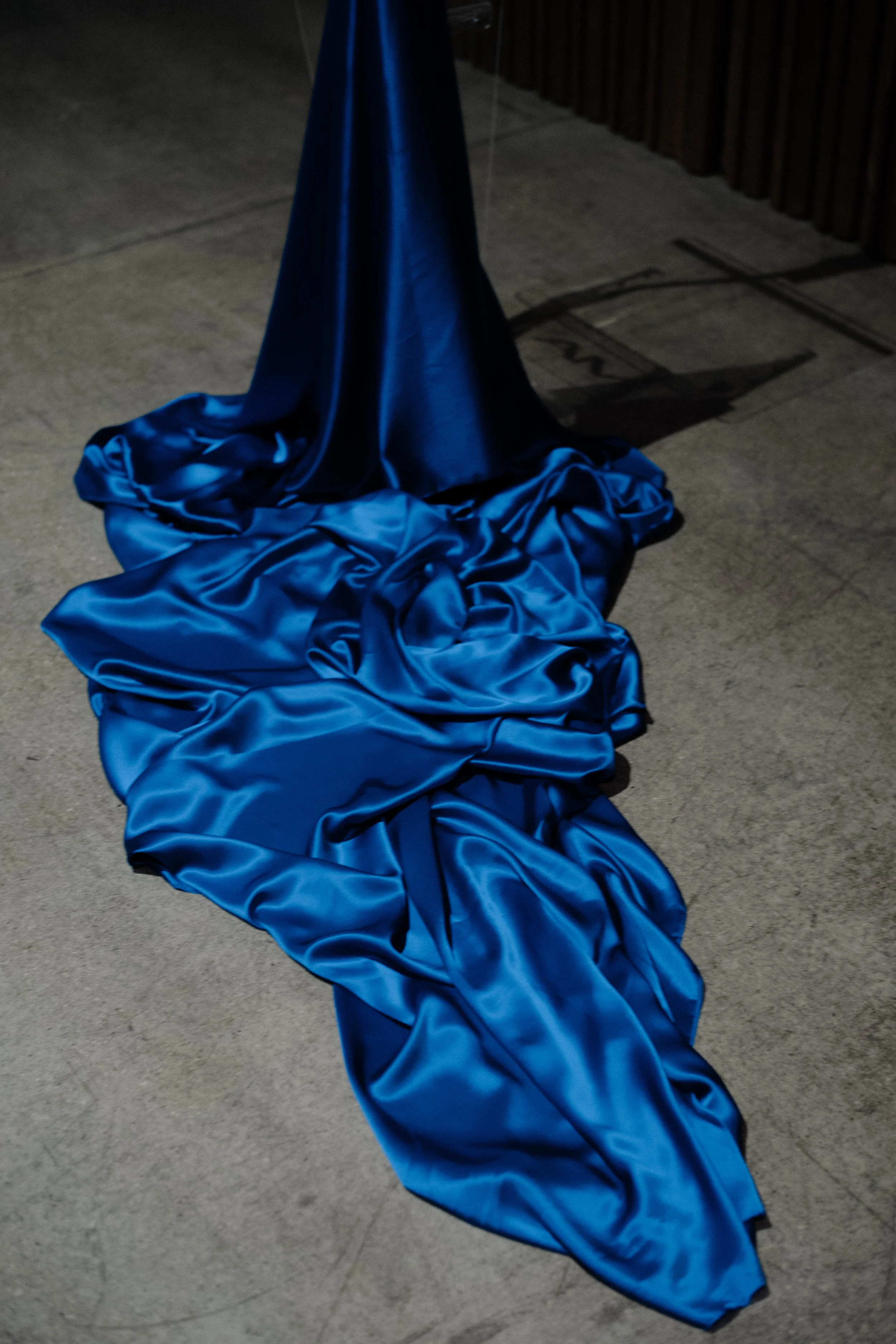 A crumpled blue silk fabric on concrete ground.