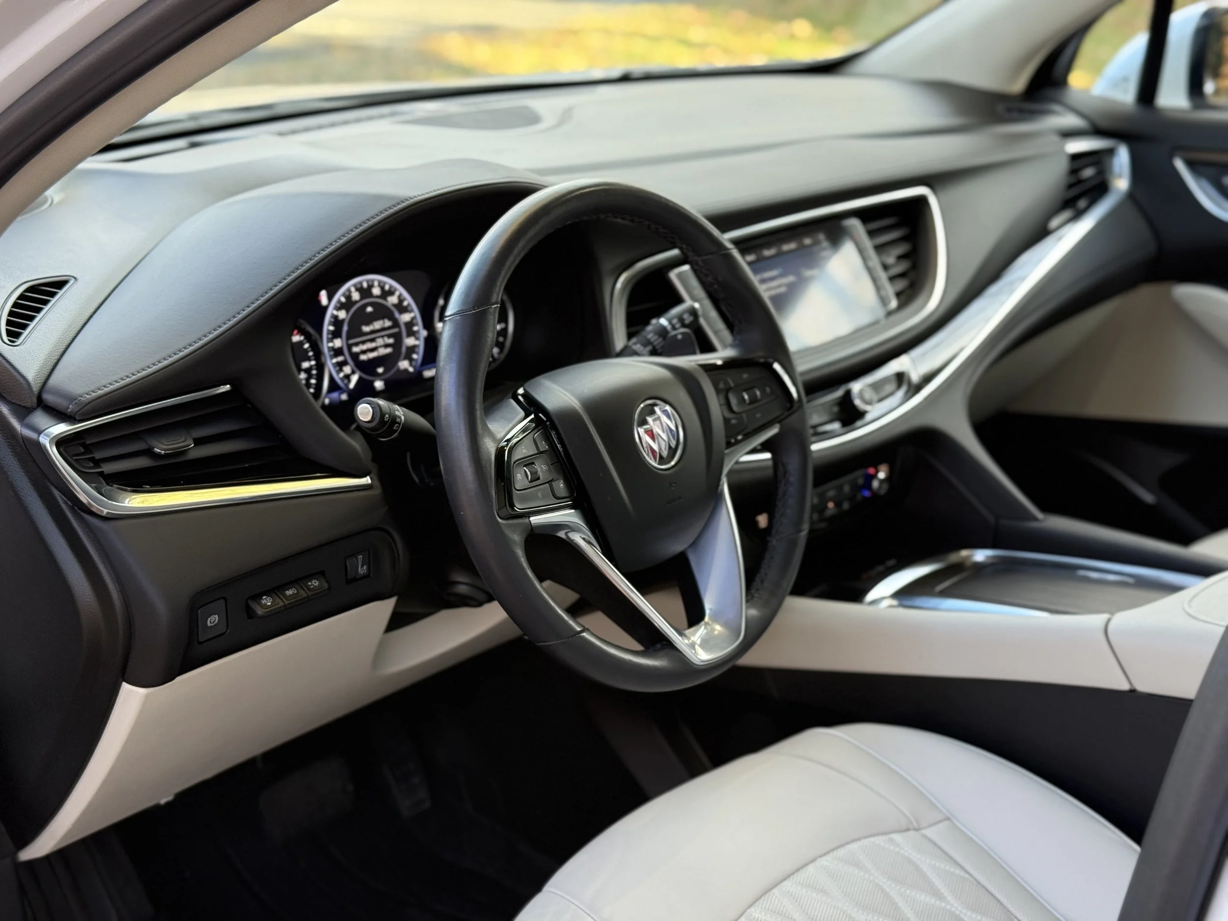 Interior of a modern Buick vehicle, focusing on the dashboard, steering wheel, and front seats, with a digital instrument cluster and touchscreen display.