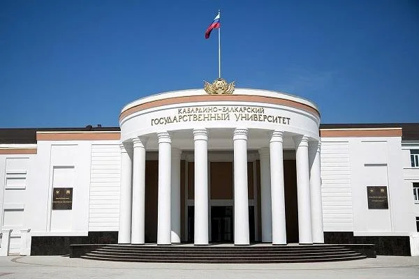 The front entrance of Kuban-Balaksky State University with white columns, a Russian flag on top, and the university's name written in Russian above the entrance.
