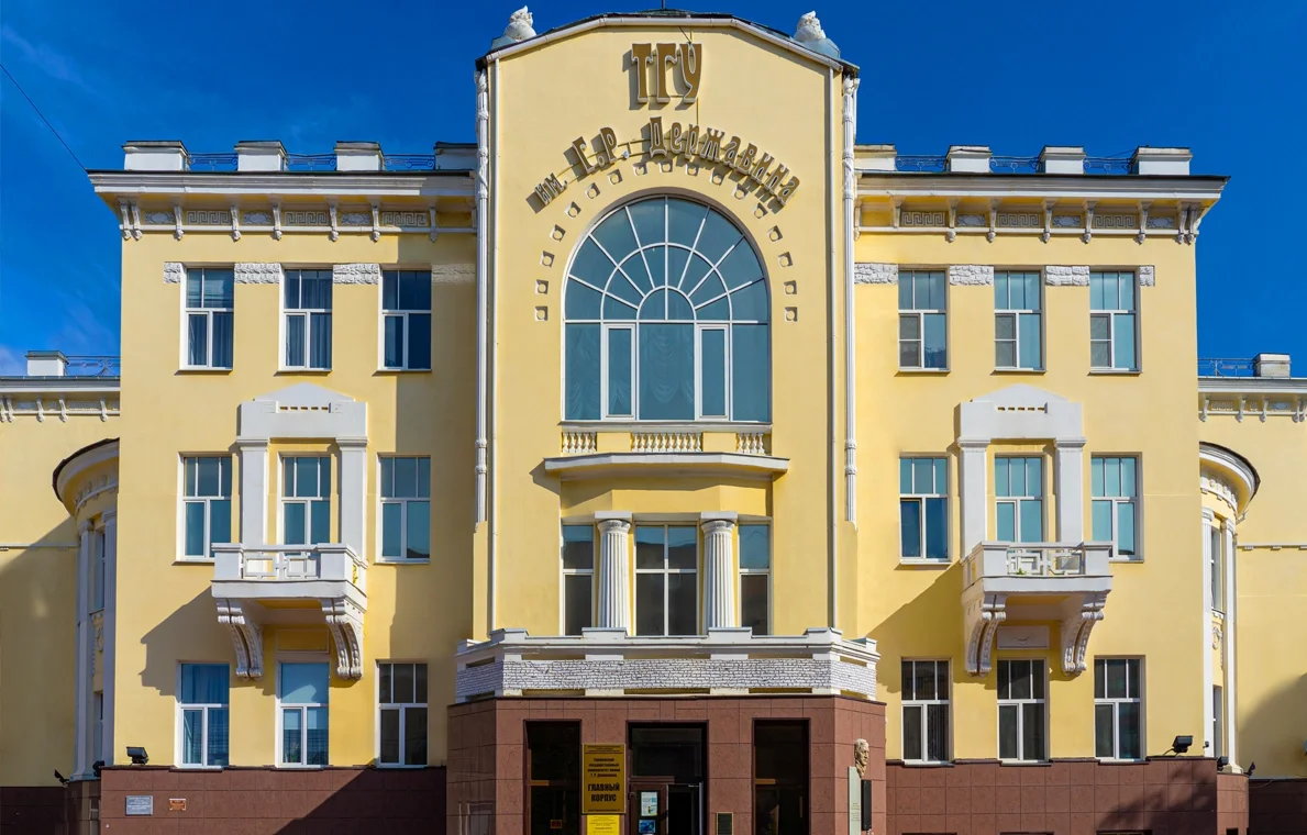 Yellow building with classical architectural details, multiple windows, decorative columns, and a large arched window, under a blue sky.
