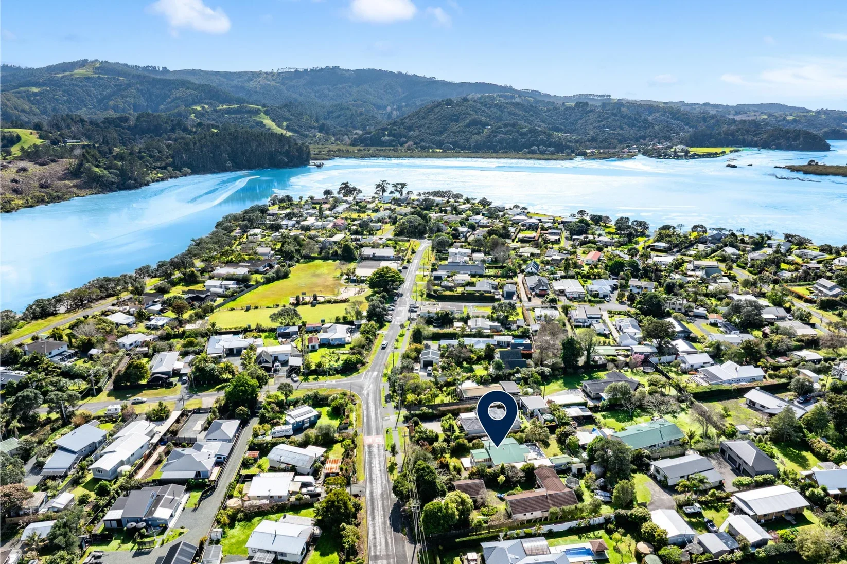 Aerial view of Point Wells residential neighborhood near a river with green hills of Whangateau in the background.