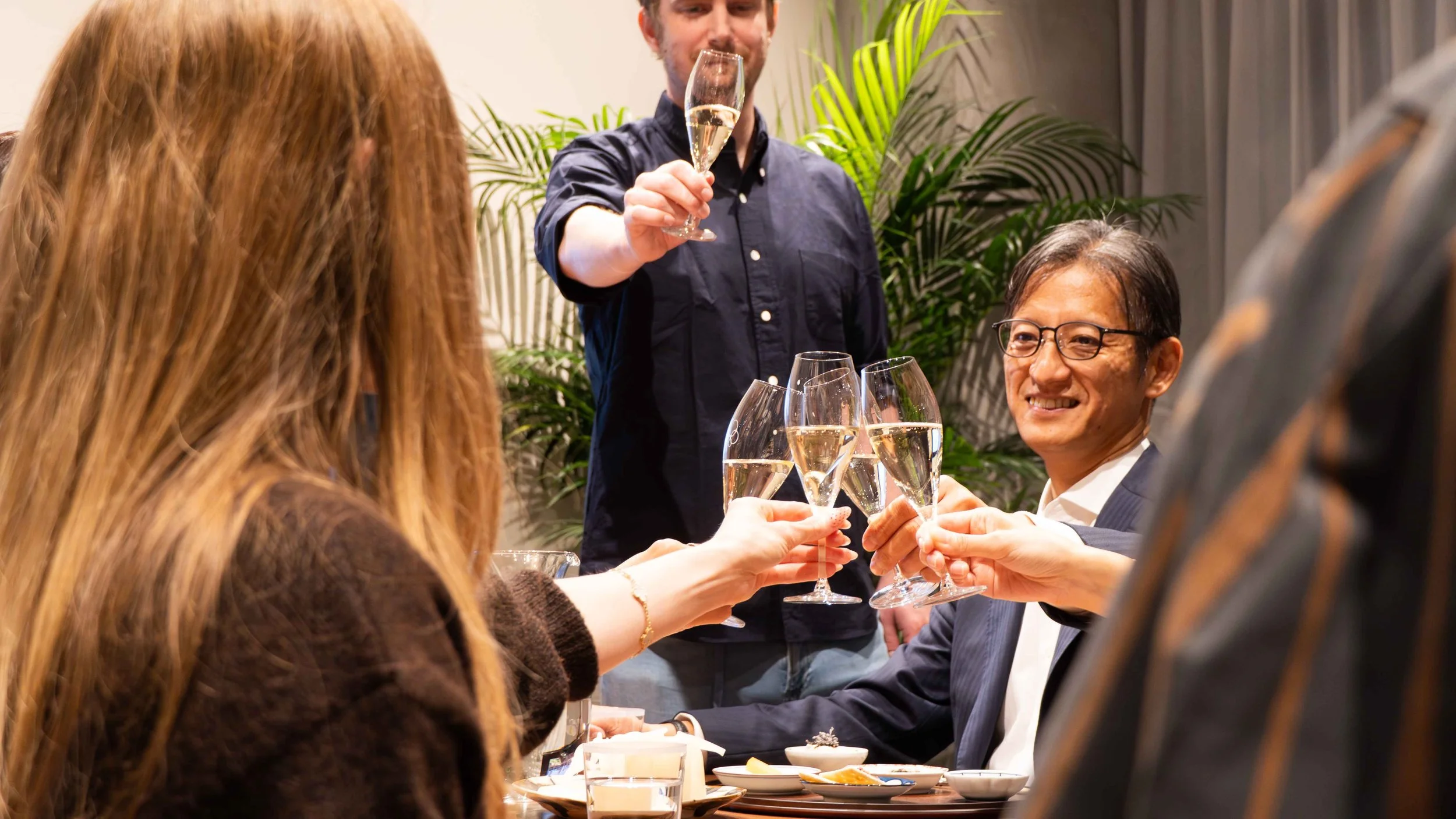 Guests raising glasses of Japanese sparkling wine to begin the tasting seminar at THREE GRAPES Tokyo.