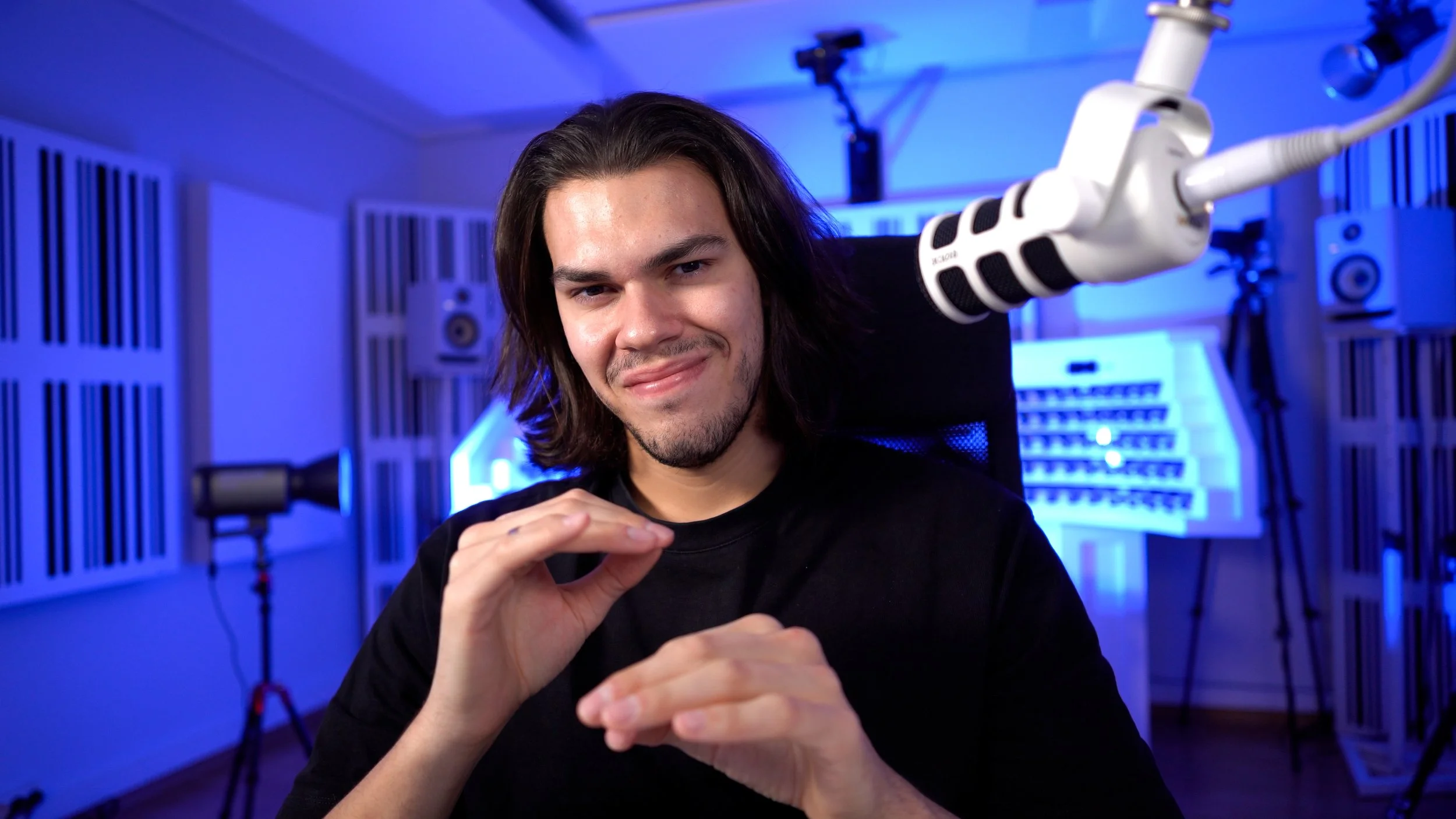 Giulio Lucciola speaking to the camera during a talk recording in his studio, with microphone and blue lighting visible.