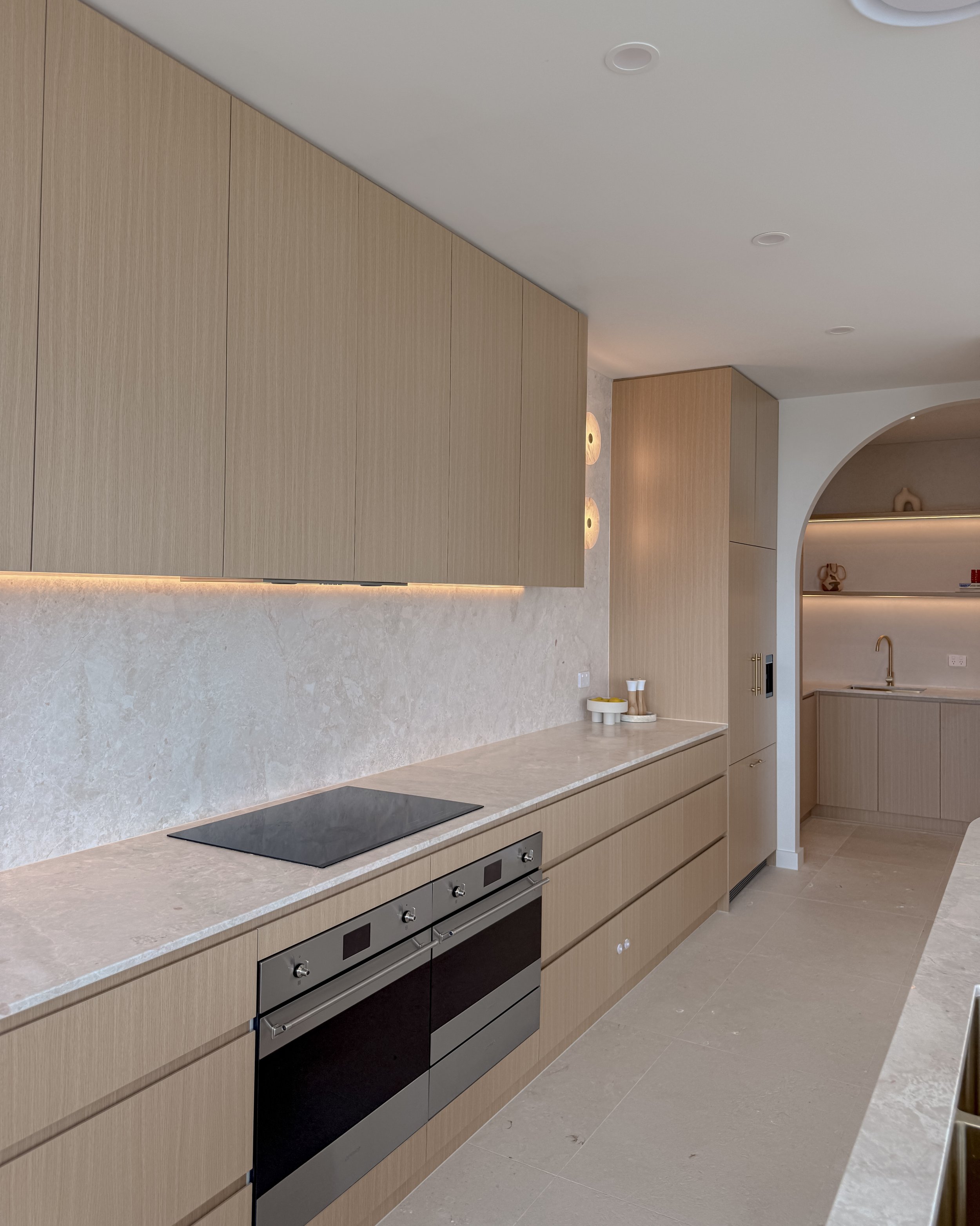 Modern coastal kitchen and pantry designed by TID Studio. Contemporary kitchen with curved cabinetry and fluted stone kitchen island. Sydney interior designer
