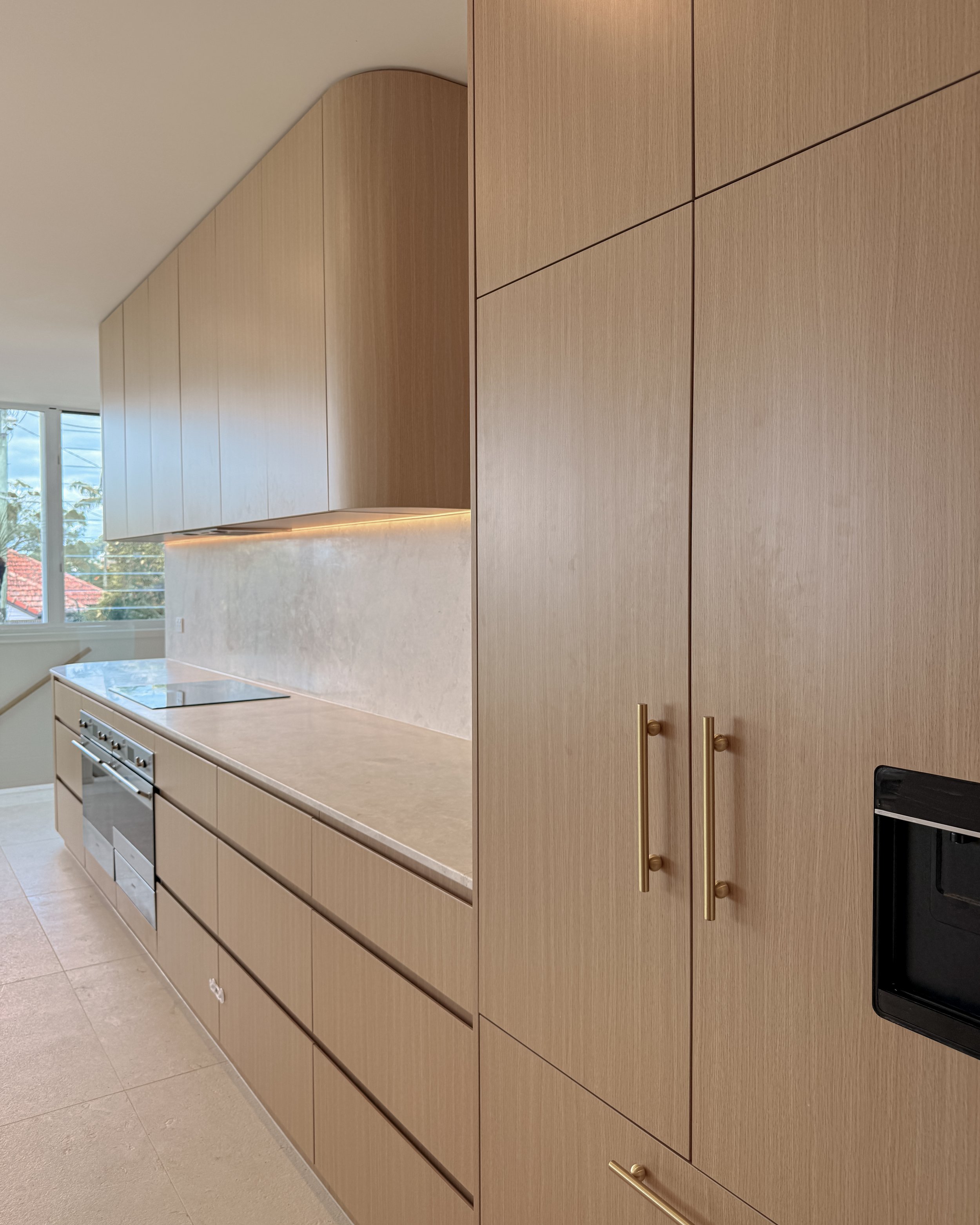 Modern coastal kitchen and pantry designed by TID Studio. Contemporary kitchen with curved cabinetry and fluted stone kitchen island. Sydney interior designer