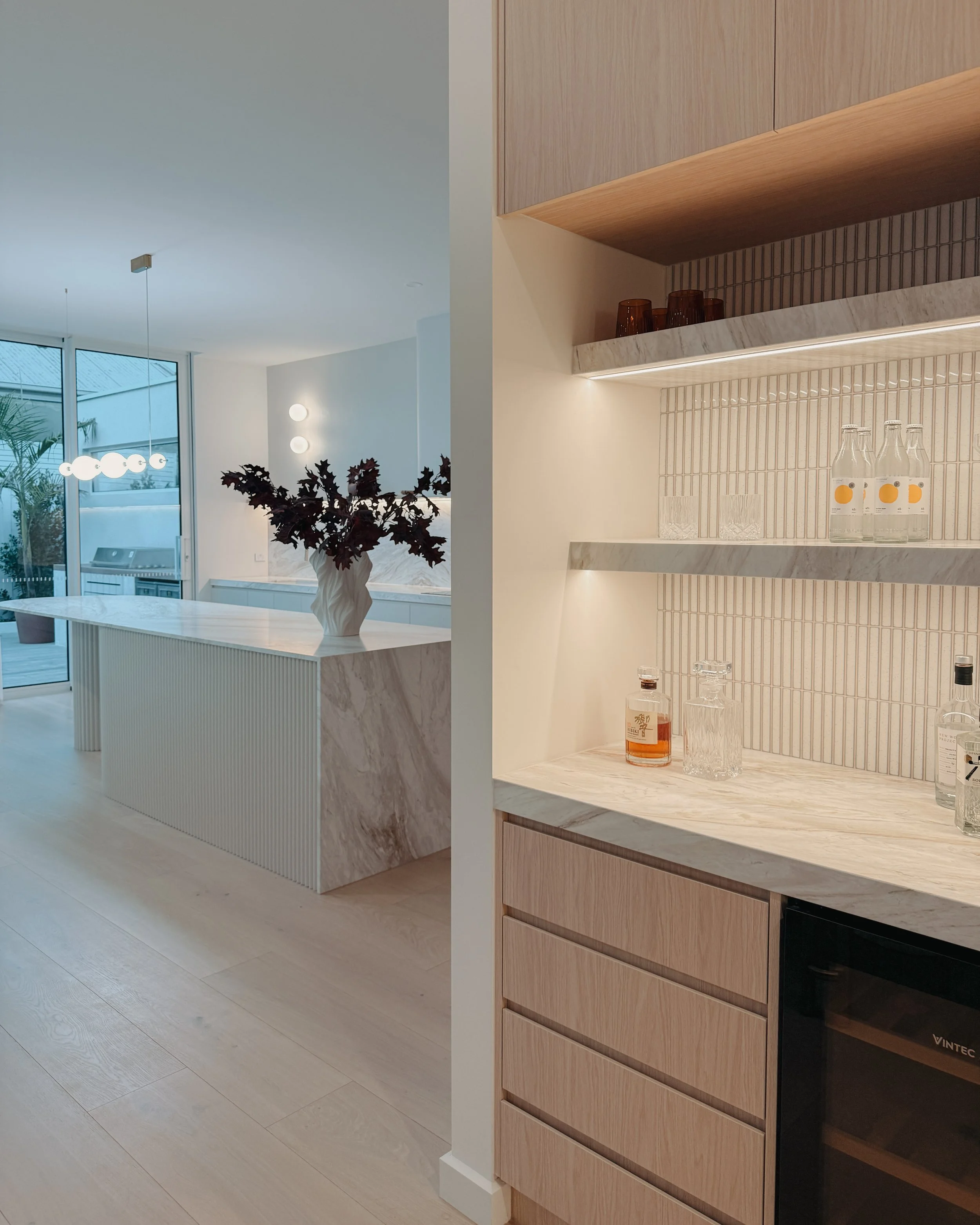 Contemporary soft-curved kitchen with fluted island, light timber cabinetry, and sculptural rangehood in a minimal-luxe Melbourne new-build. Designed by TID Studio, interior design in Sydney