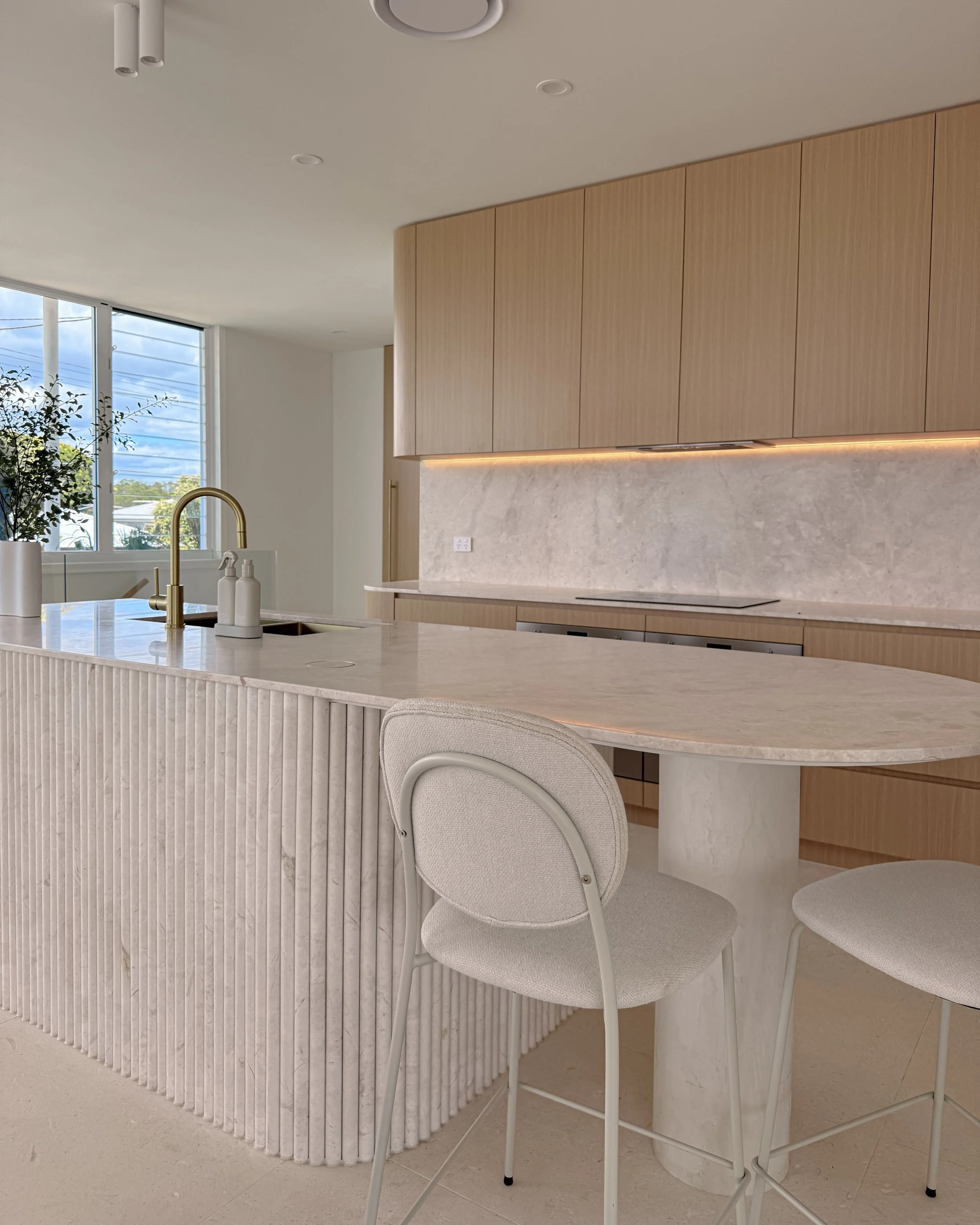 Modern coastal kitchen and pantry designed by TID Studio. Contemporary kitchen with curved cabinetry and fluted stone kitchen island. Sydney interior designer