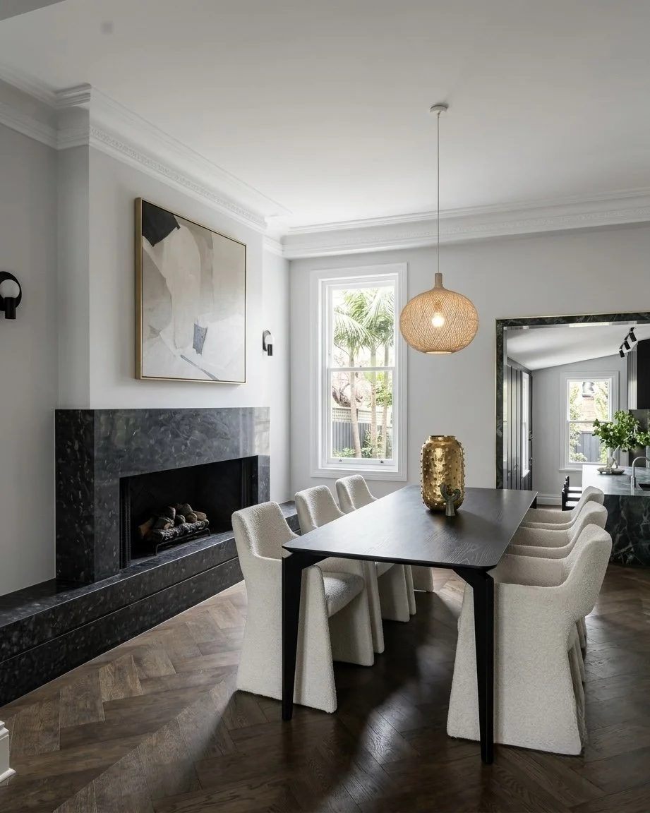 Dining room with black table, stone fireplace, and heritage mouldings in Sydney terrace home