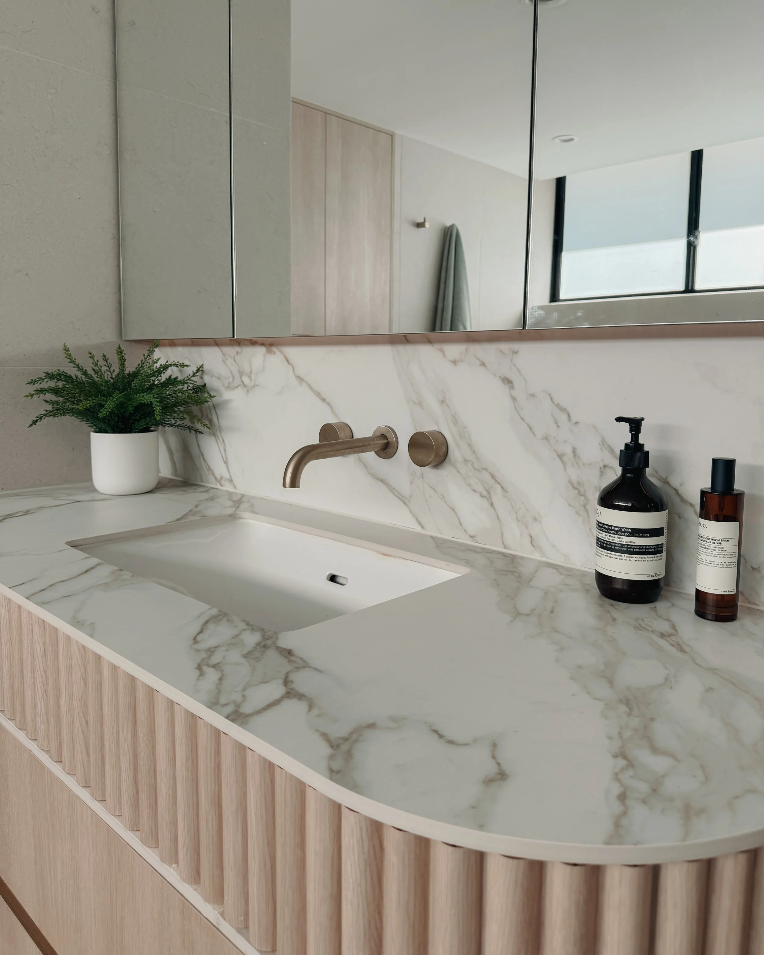 Modern bathroom custom curved vanity, and warm timber tones, fluted timber detail — coastal apartment in Gold Coast designed by TID Studio Sydney