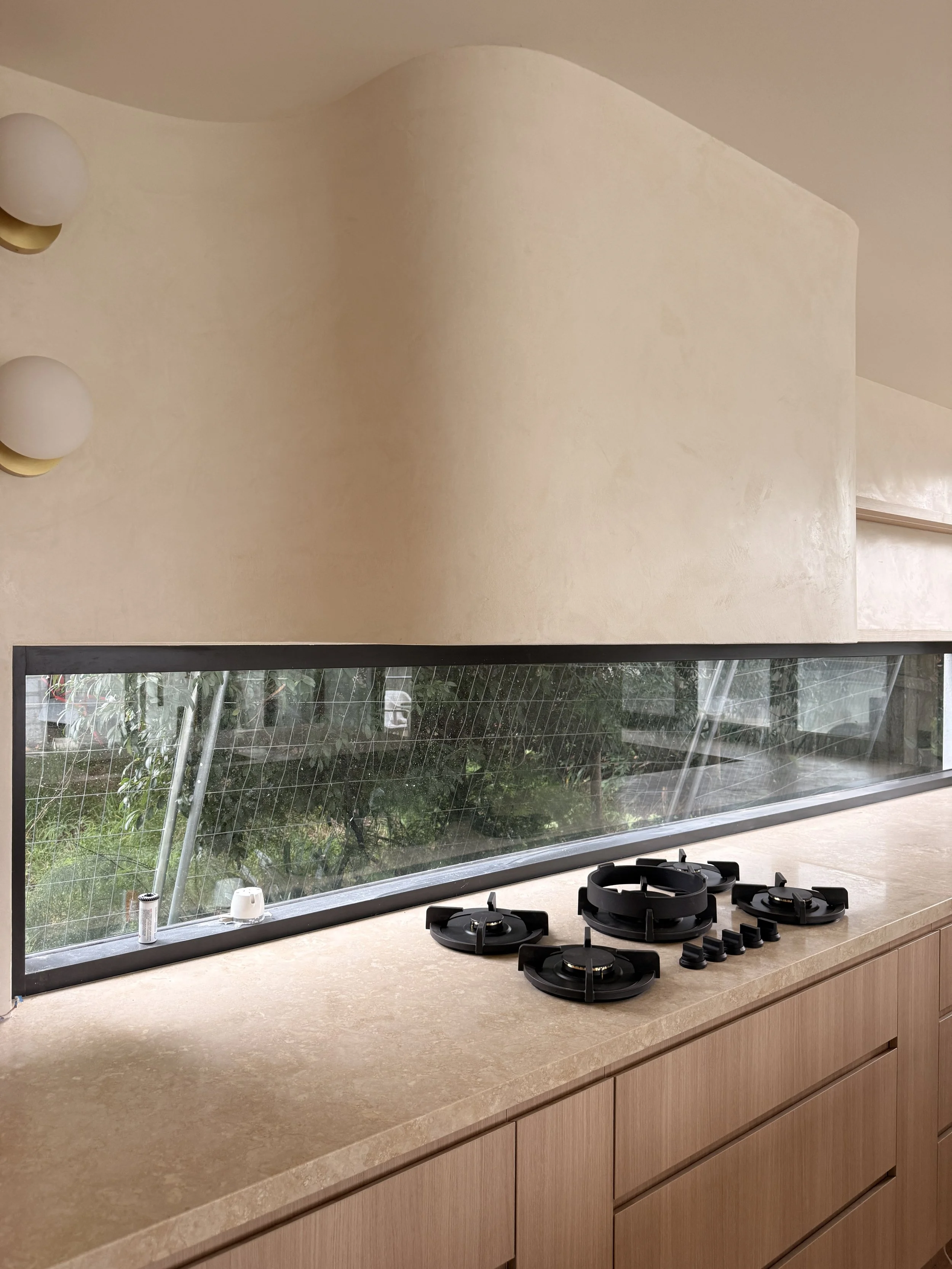 Modern coastal kitchen featuring a curved stone island, light timber cabinetry and neutral palette — Auriga Residence by TID Studio, interior designer Sydney