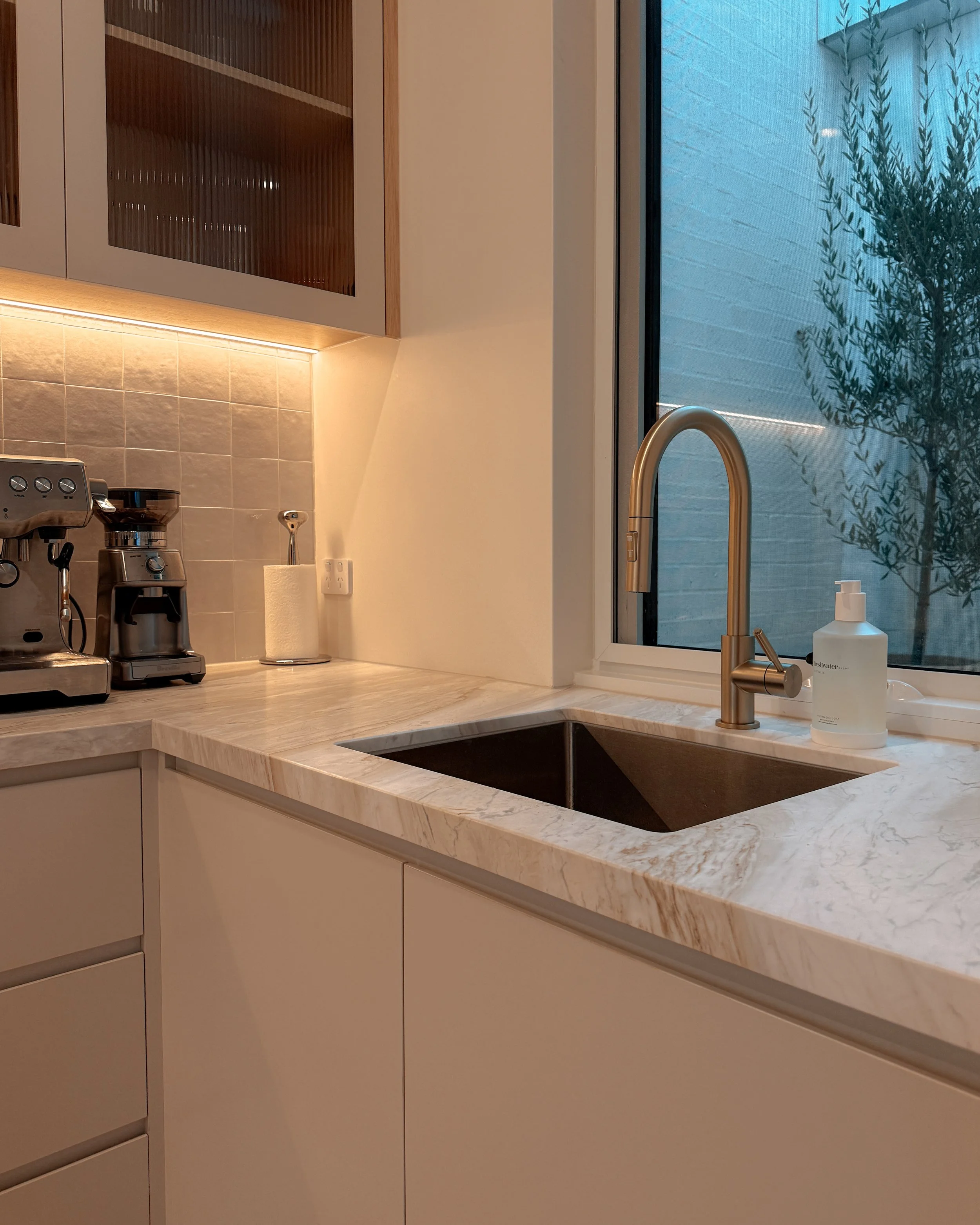 Contemporary soft-curved kitchen with fluted island, light timber cabinetry, and sculptural rangehood in a minimal-luxe Melbourne new-build. Designed by TID Studio, interior design in Sydney
