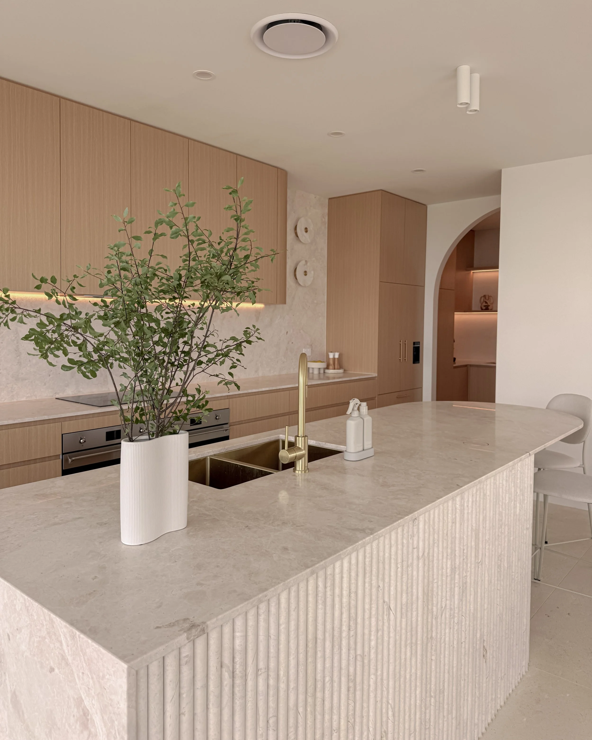 Modern coastal kitchen and pantry designed by TID Studio. Contemporary kitchen with curved cabinetry and fluted stone kitchen island. Sydney interior designer