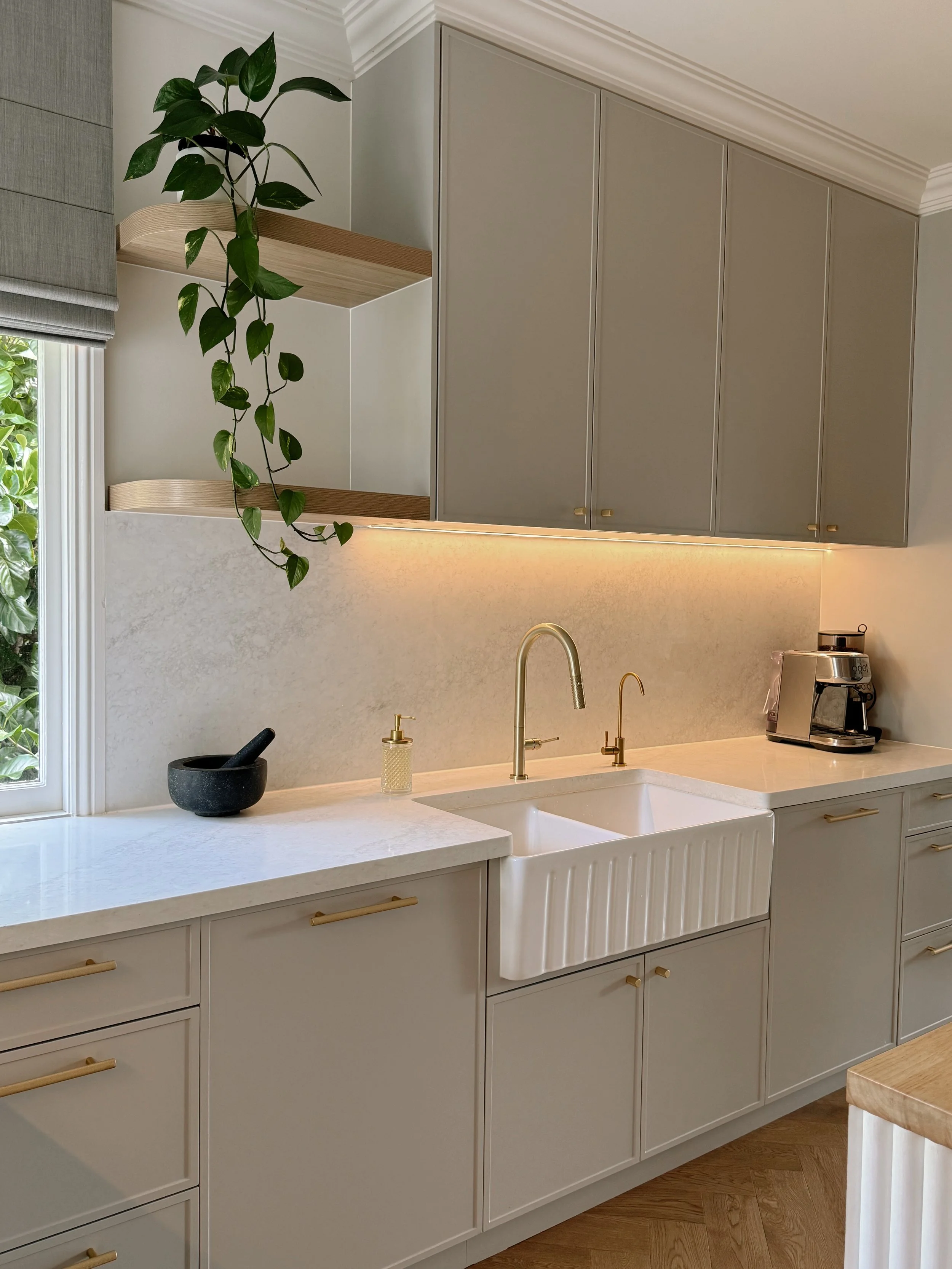 Detailed kitchen view with farmhouse sink and soft neutral stone benchtop