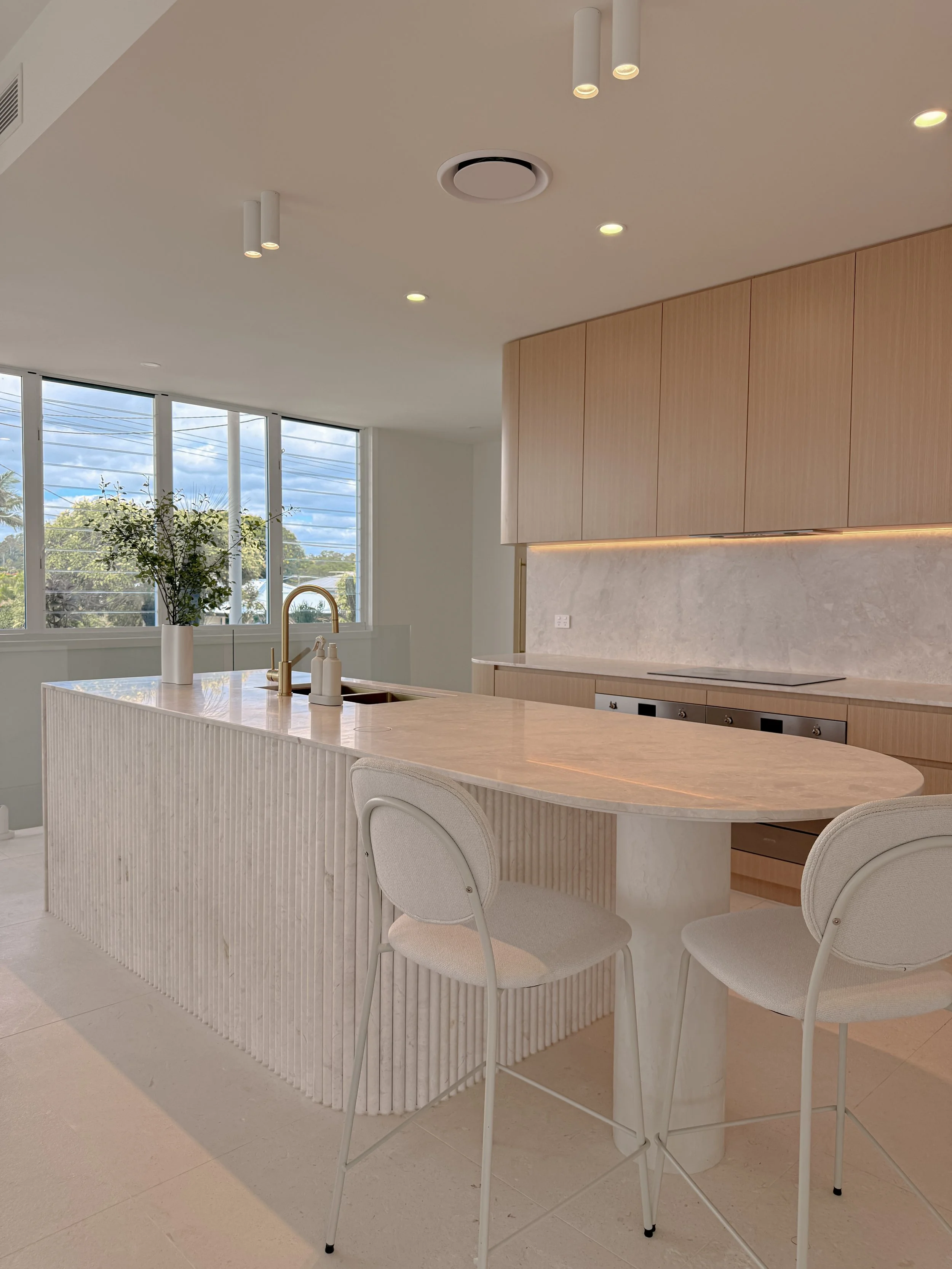 Fluted kitchen island with bar stools and brass tapware in a soft neutral Brisbane townhouse renovation
