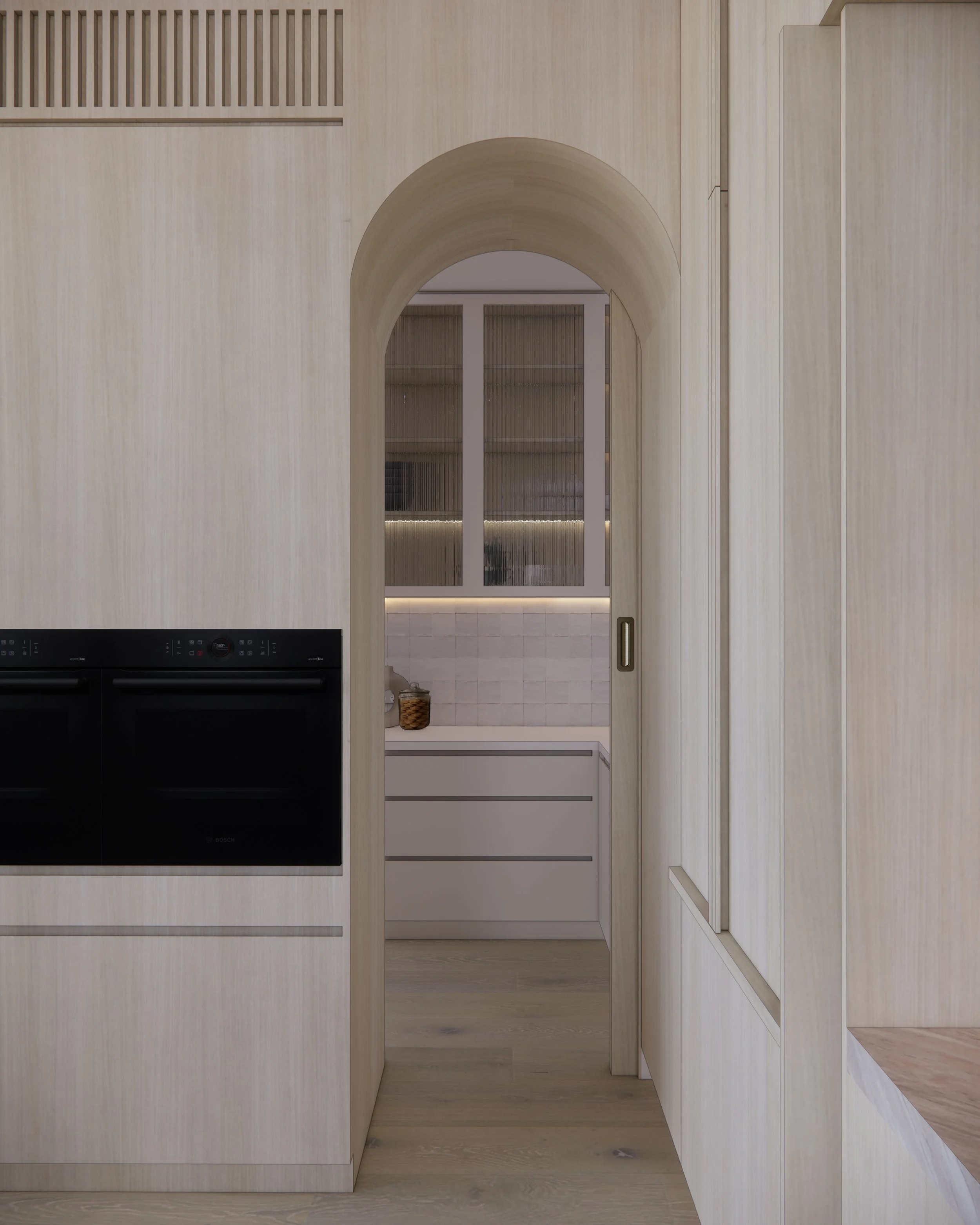 Contemporary soft-curved kitchen with fluted island, light timber cabinetry, and sculptural rangehood in a minimal-luxe Melbourne home.