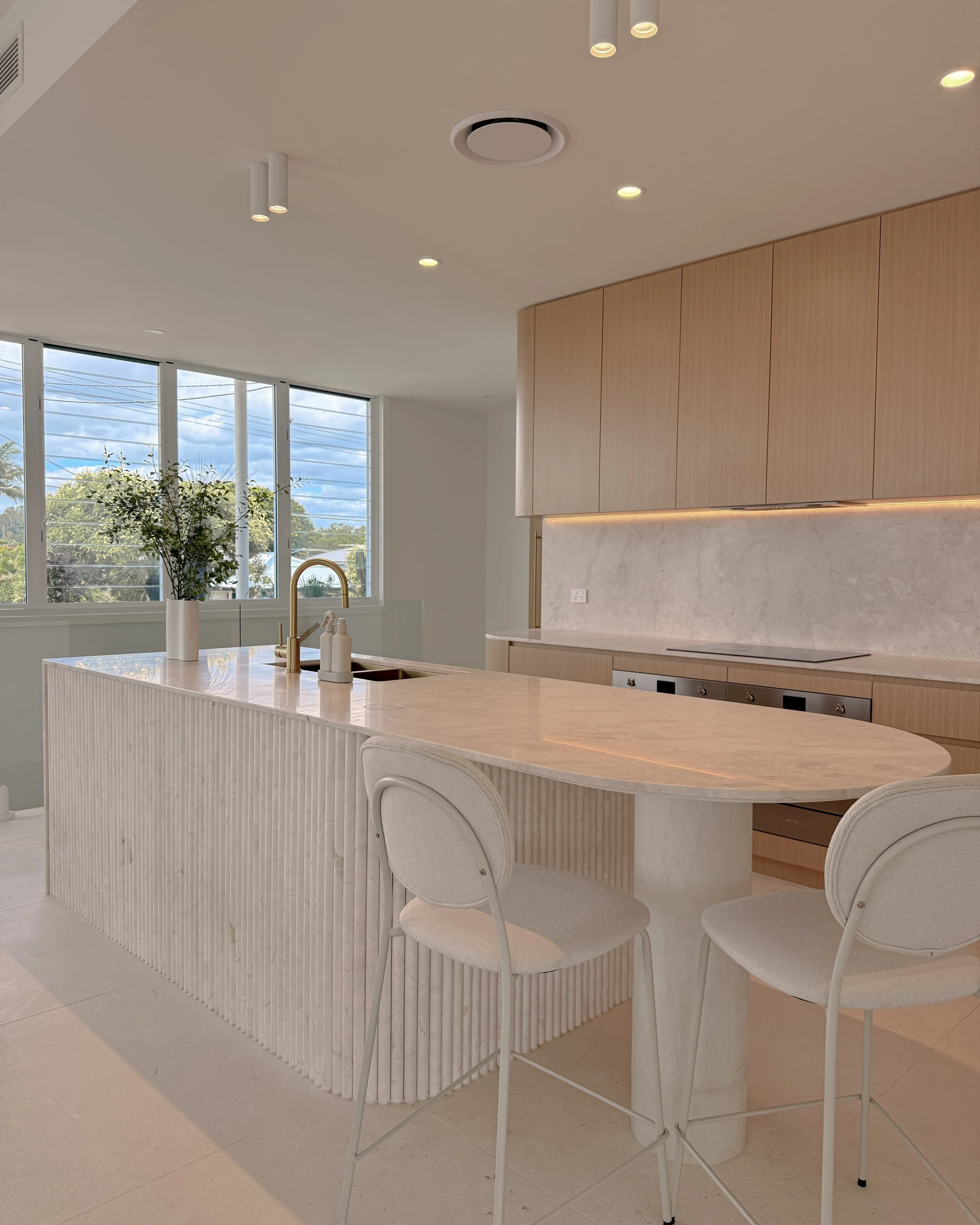 Modern coastal kitchen and pantry designed by TID Studio. Contemporary kitchen with curved cabinetry and fluted stone kitchen island. Sydney interior designer
