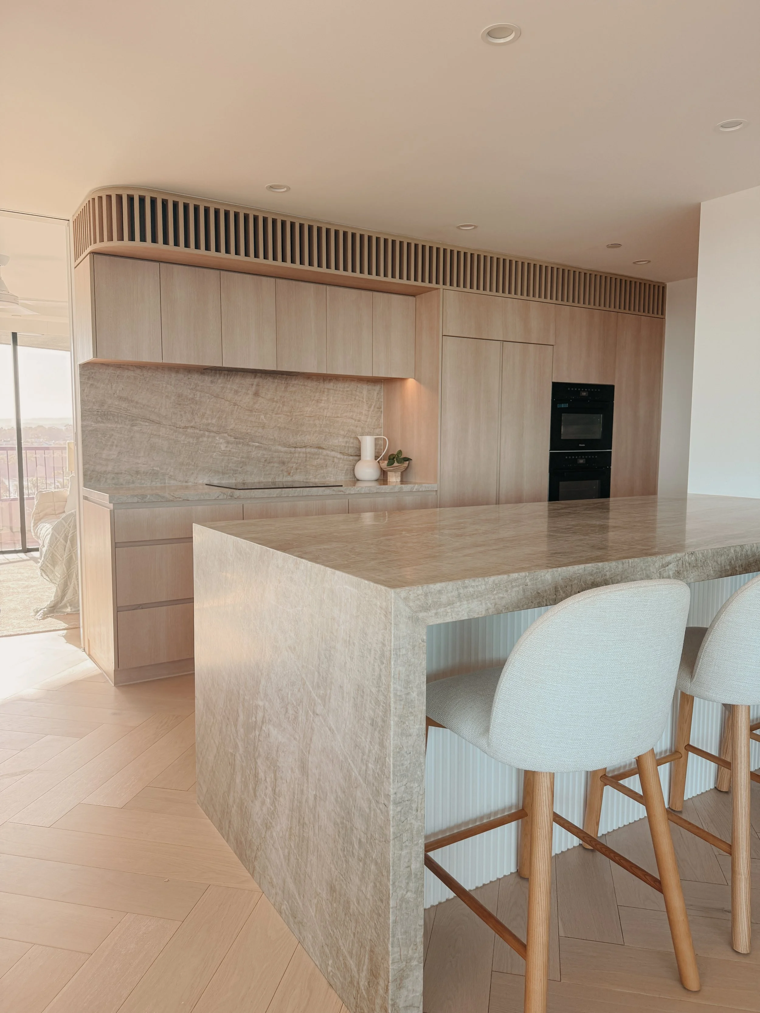 Soft neutral kitchen with ocean views and minimalist joinery by TID Studio