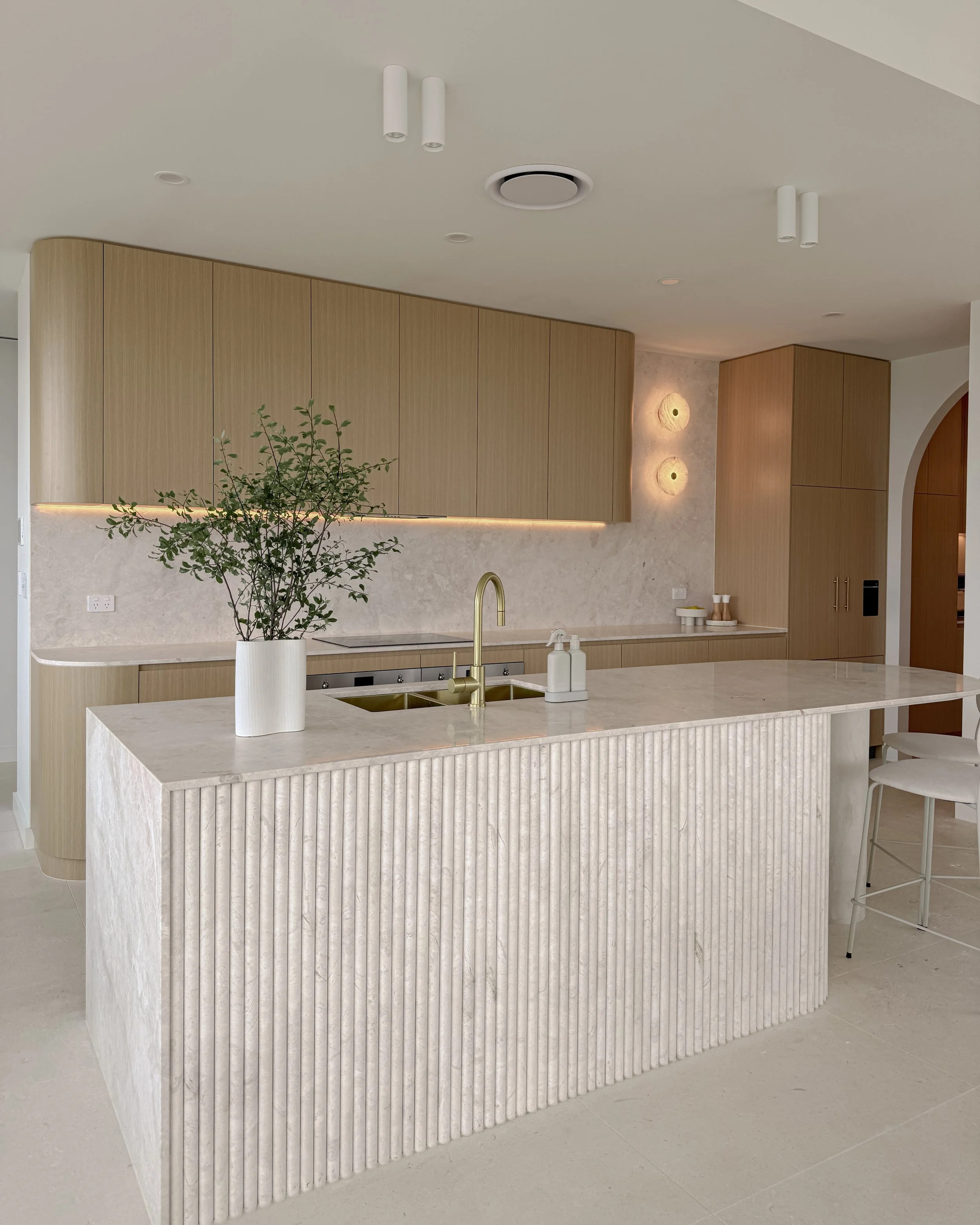 Curved light-timber kitchen with marble-look benchtop and soft coastal palette designed by TID Studio in Brisbane