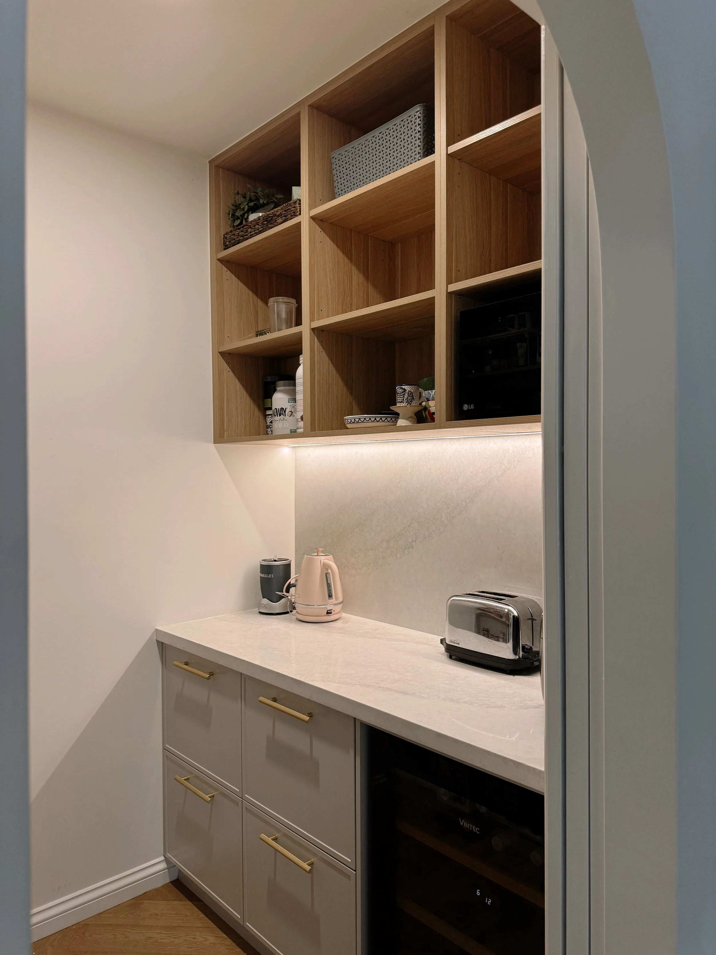 Functional walk-in pantry layout featuring cabinetry, shelving and appliance storage