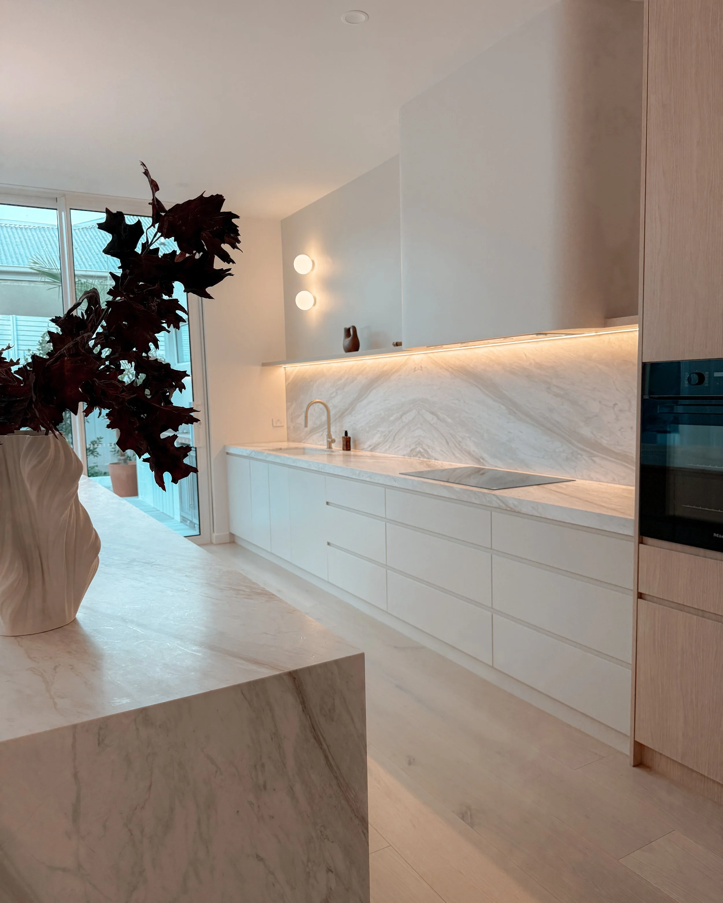Contemporary soft-curved kitchen with fluted island, light timber cabinetry, and sculptural rangehood in a minimal-luxe Melbourne new-build. Designed by TID Studio, interior design in Sydney