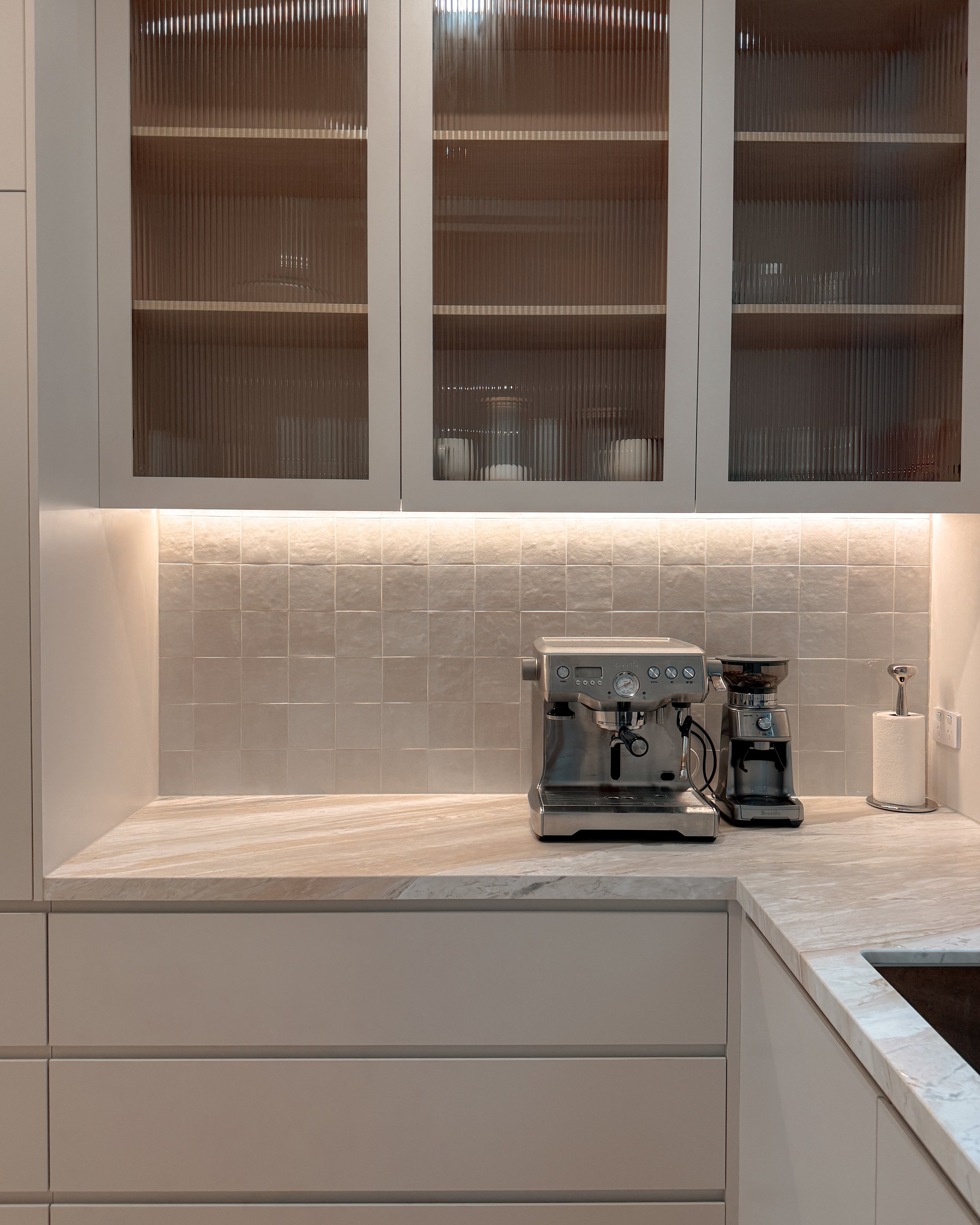 Contemporary soft-curved kitchen with fluted island, light timber cabinetry, and sculptural rangehood in a minimal-luxe Melbourne new-build. Designed by TID Studio, interior design in Sydney