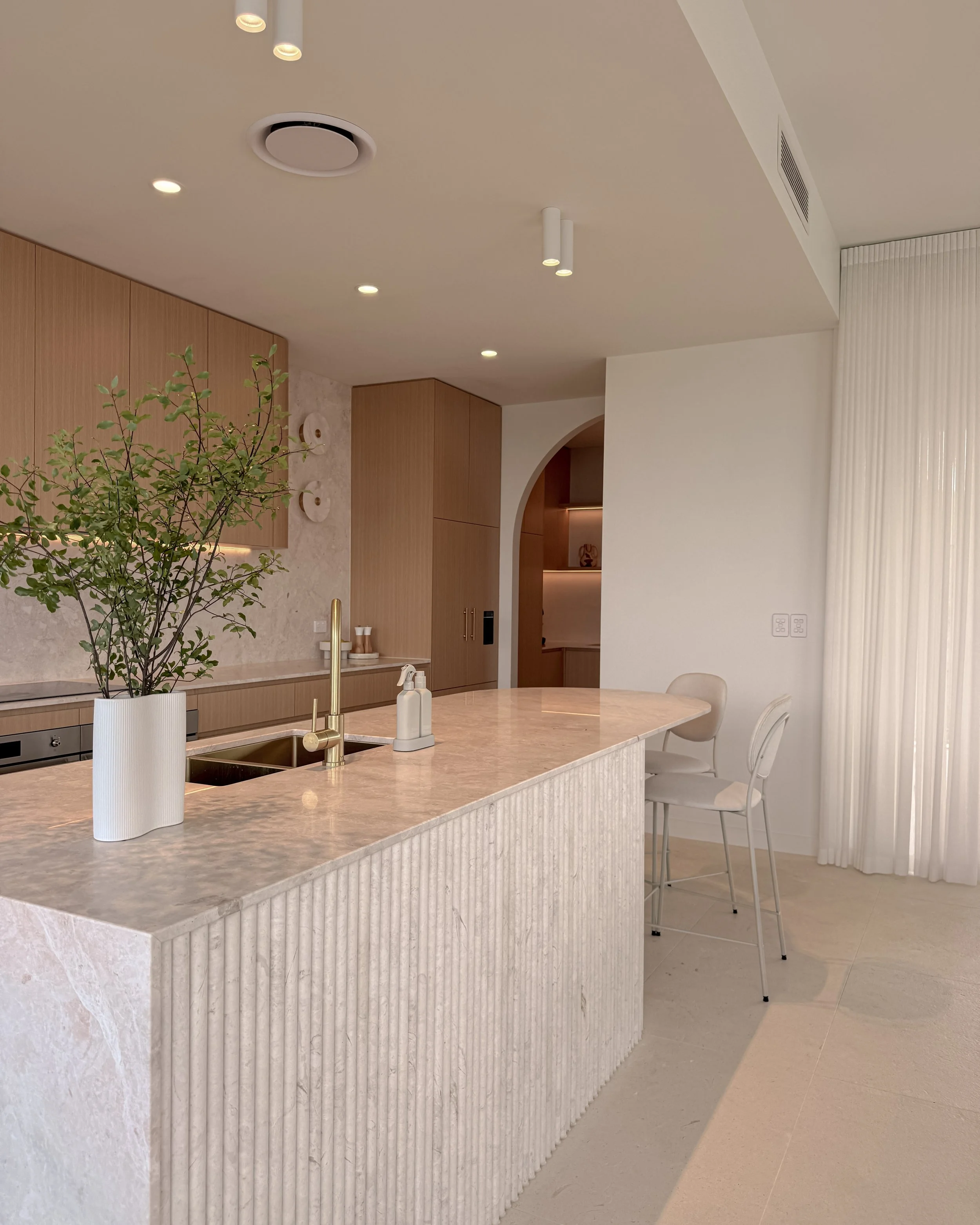 Modern coastal kitchen and pantry designed by TID Studio. Contemporary kitchen with curved cabinetry and fluted stone kitchen island. Sydney interior designer