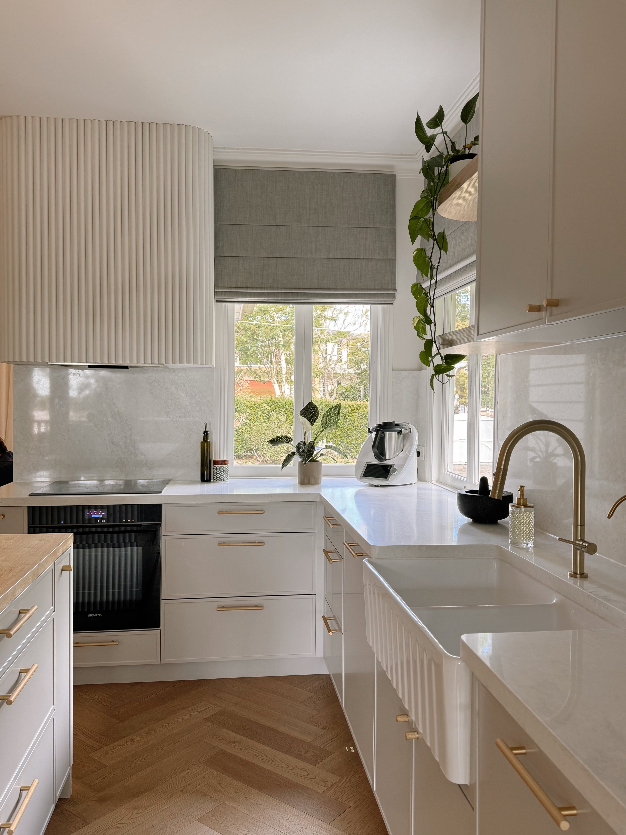 Detailed kitchen view with farmhouse sink and soft neutral stone benchtop