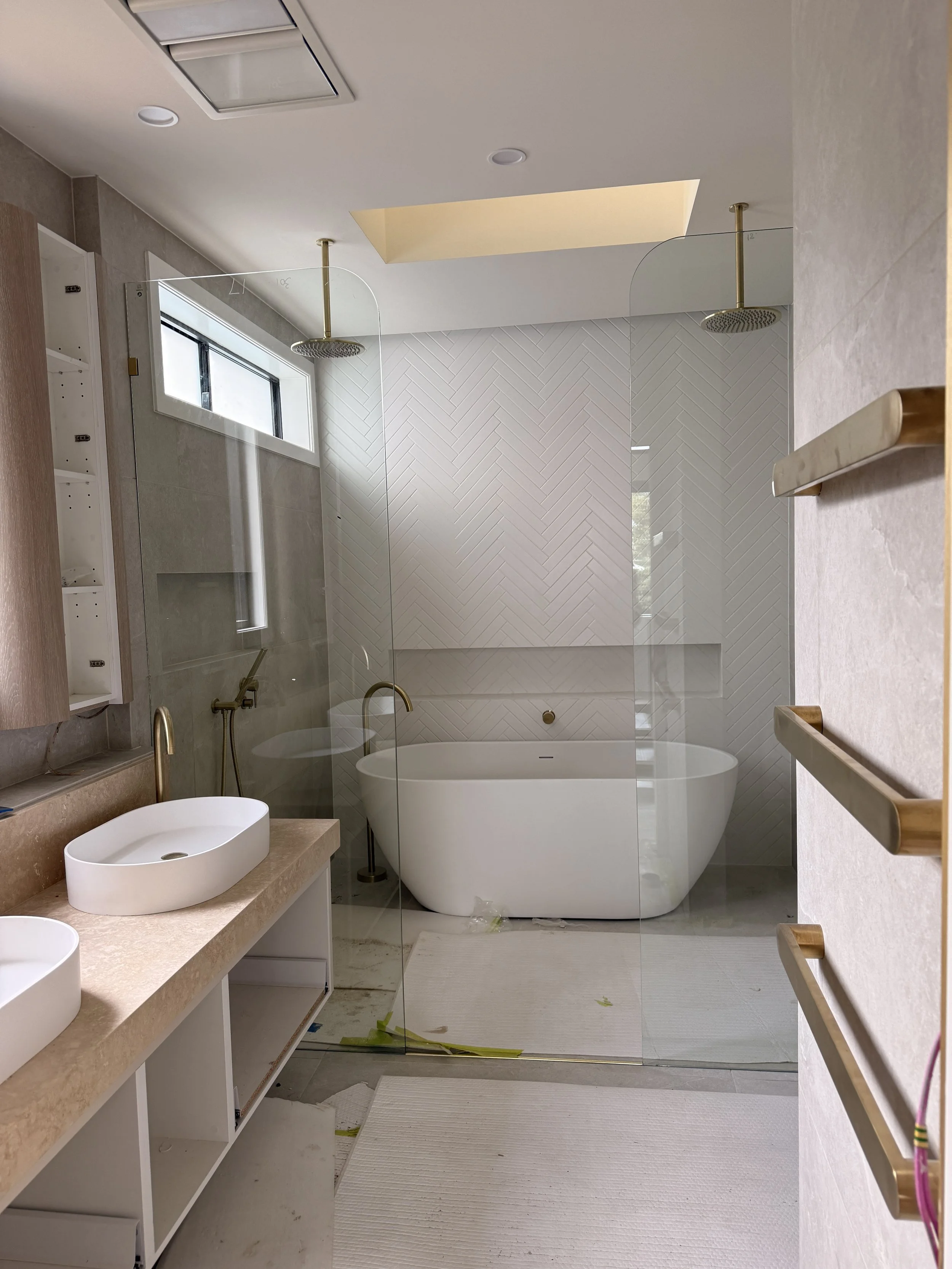 Modern master bathroom featuring curved vanity, travertine textures and brushed brass fixtures — Auriga Residence by TID Studio, interior designer Sydney