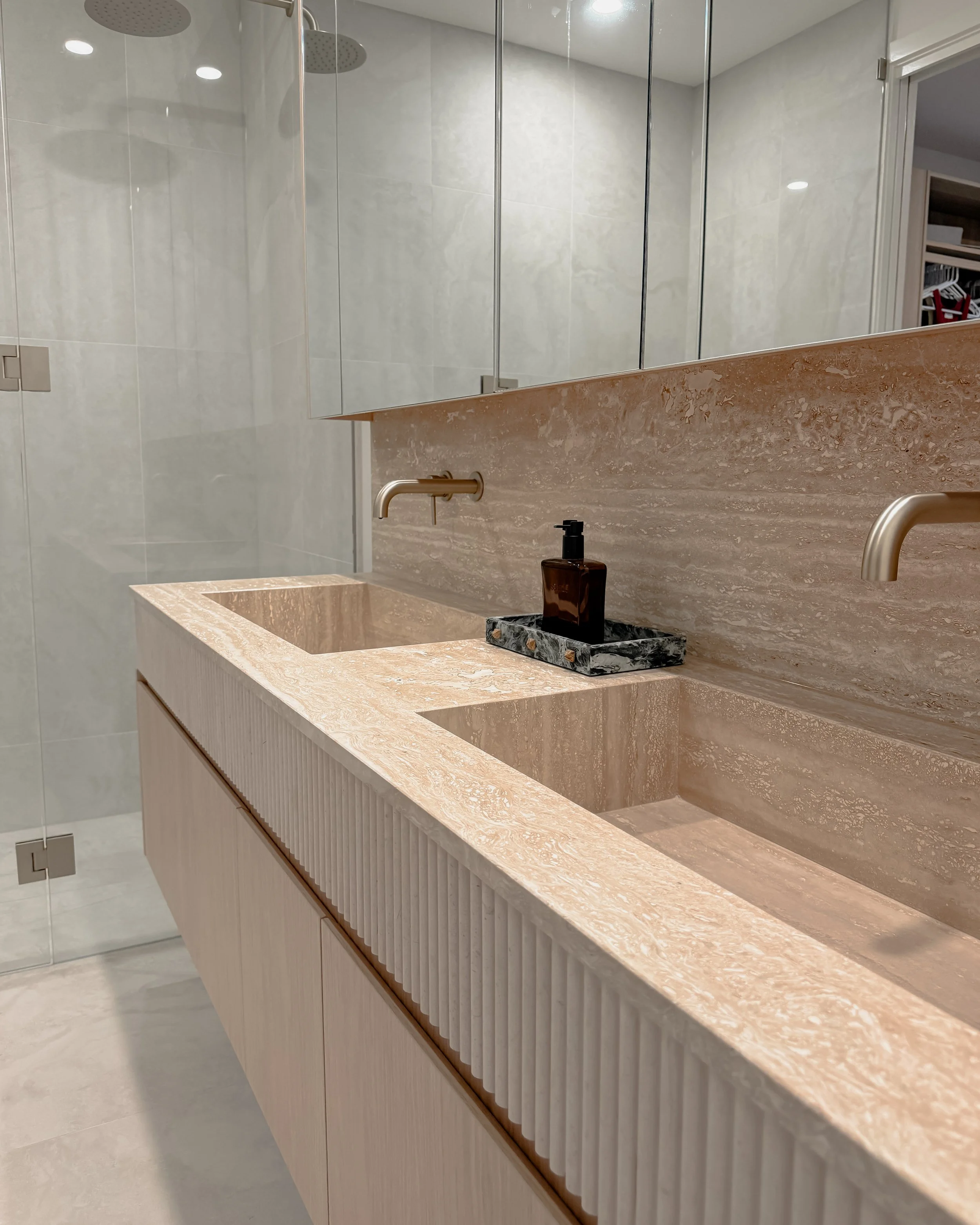 Contemporary Master Ensuite with custom stone sink, fluted travertine, double vanity, double shower in Melbourne new-build. Designed by TID Studio, interior design in Sydney